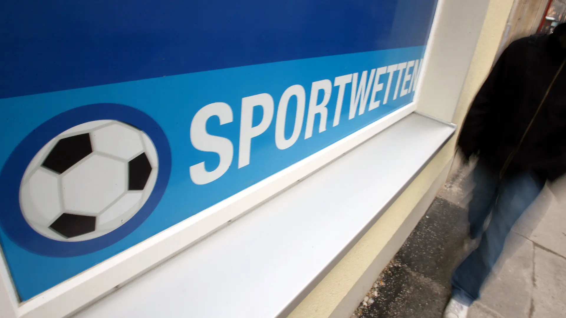 ARCHIV - Ein Mann läuft am Freitag (17.03.2006) an einem Wettbüro für Sportwetten in Augsburg vorbei (Illustration zum Thema Sportwetten). Fußball-Wetten sind in Deutschland erneut in die Schlagzeilen geraten. Foto: Karl-Josef Hildenbrand/dpa (zu dpa «Skandal erschüttert Österreich-Fußball - Drei Festnahmen » am 12.11.2013) +++(c) dpa - Bildfunk+++