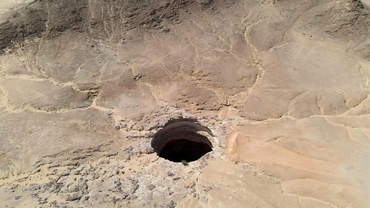 An aerial view taken on June 6, 2021 shows the Well of Barhout known as the "Well of Hell" in the desert of Yemen's Al-Mahra province. - Closer to the border with Oman than to the capital Sanaa 1,300 kilometres (800 miles) away, the giant hole in the desert of Al-Mahra province is 30 metres wide and thought to be anywhere between 100 and 250 metres deep. Local folklore says it was created as a prison for the demons -- a reputation bolstered by the foul odours rising from its depths. (Photo by - / AFP)