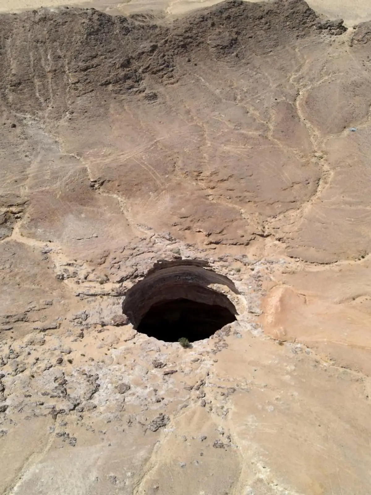 An aerial view taken on June 6, 2021 shows the Well of Barhout known as the "Well of Hell" in the desert of Yemen's Al-Mahra province. - Closer to the border with Oman than to the capital Sanaa 1,300 kilometres (800 miles) away, the giant hole in the desert of Al-Mahra province is 30 metres wide and thought to be anywhere between 100 and 250 metres deep. Local folklore says it was created as a prison for the demons -- a reputation bolstered by the foul odours rising from its depths. (Photo by - / AFP)
