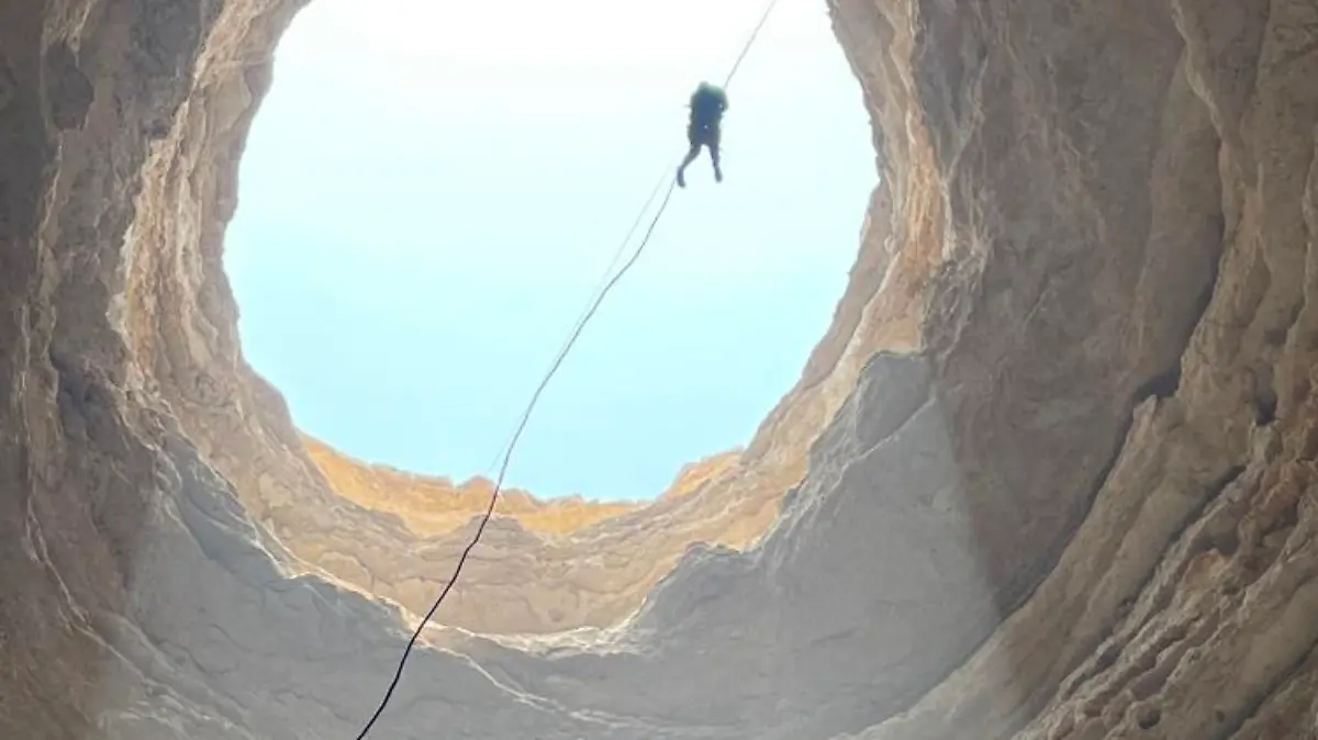 A handout picture taken by the Oman Cave Exploration Team on September 15, 2021, shows one of the team's cavers abseiling down the Barhout well, a sinkhole known as the "Well of Hell" in the desert of Yemen's Al-Mahra province. - A team of Omani cavers has made what is believed to be the first descent to the bottom of the forbidding sinkhole, whose dark, round aperture creates a 30m. (100 feet) wide hole, plunging approximately 112m. (367 feet) below the surface, forming a natural wonder shunned by many locals, who believe it is a prison for genies. (Photo by - / Oman Cave Exploration Team / AFP) / == RESTRICTED TO EDITORIAL USE - MANDATORY CREDIT "AFP PHOTO / HO / OMAN CAVE EXPLORATION TEAM (OCET)" - NO MARKETING NO ADVERTISING CAMPAIGNS - DISTRIBUTED AS A SERVICE TO CLIENTS ==