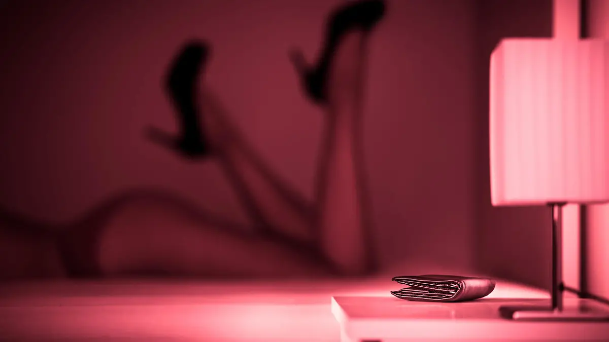 Prostituierte oder Sexarbeiterin auf dem Bett im Bordell mit sexy Beinen und hochhackigen Schuhen.
