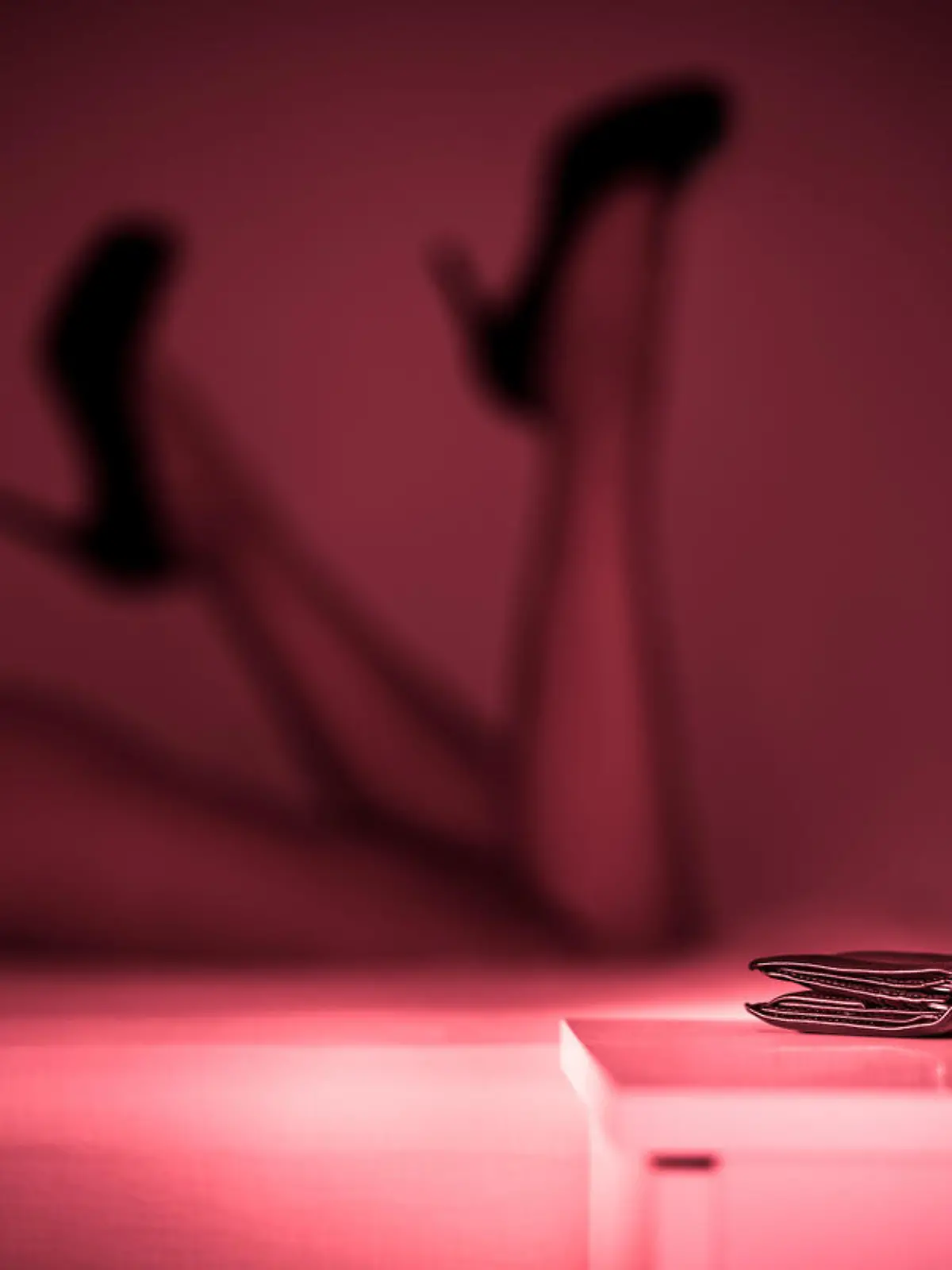 Prostituierte oder Sexarbeiterin auf dem Bett im Bordell mit sexy Beinen und hochhackigen Schuhen.