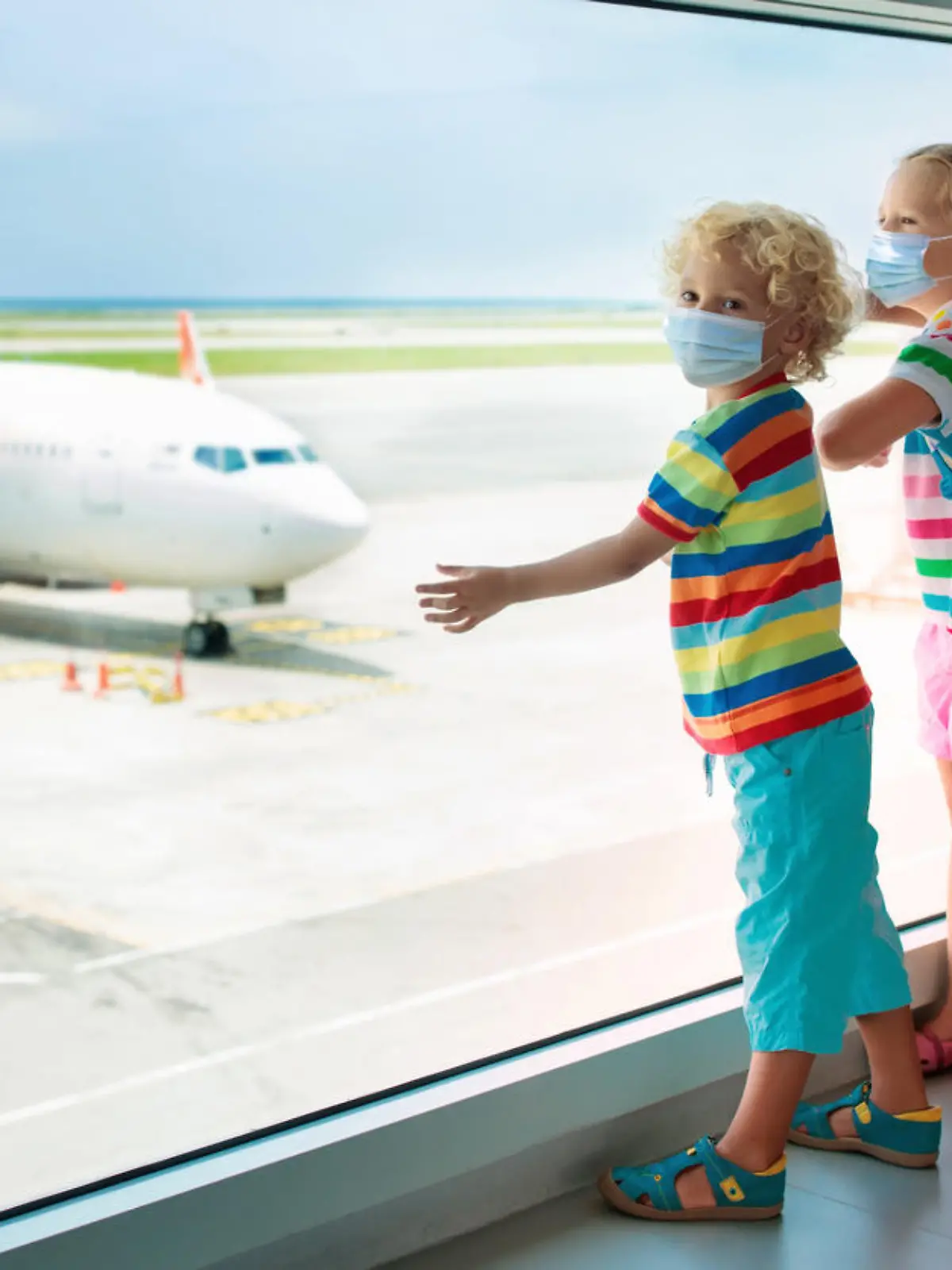 Family in airport in face mask. Virus outbreak. Coronavirus and flu pandemic. Safe travel with young child and baby. Kids boarding airplane in surgical masks.