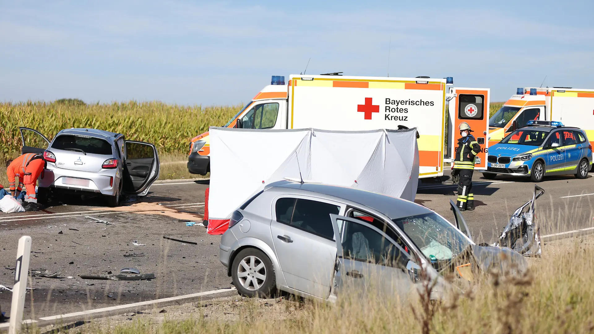 Nach einem Frontalzusammenstoß stehen zwei Autos und mehrere Rettungsfahrzeuge auf einer Bundesstraße. Drei Menschen sind bei dem Verkehrsunfall auf der Bundesstraße 2 in Mittelfranken ums Leben gekommen.