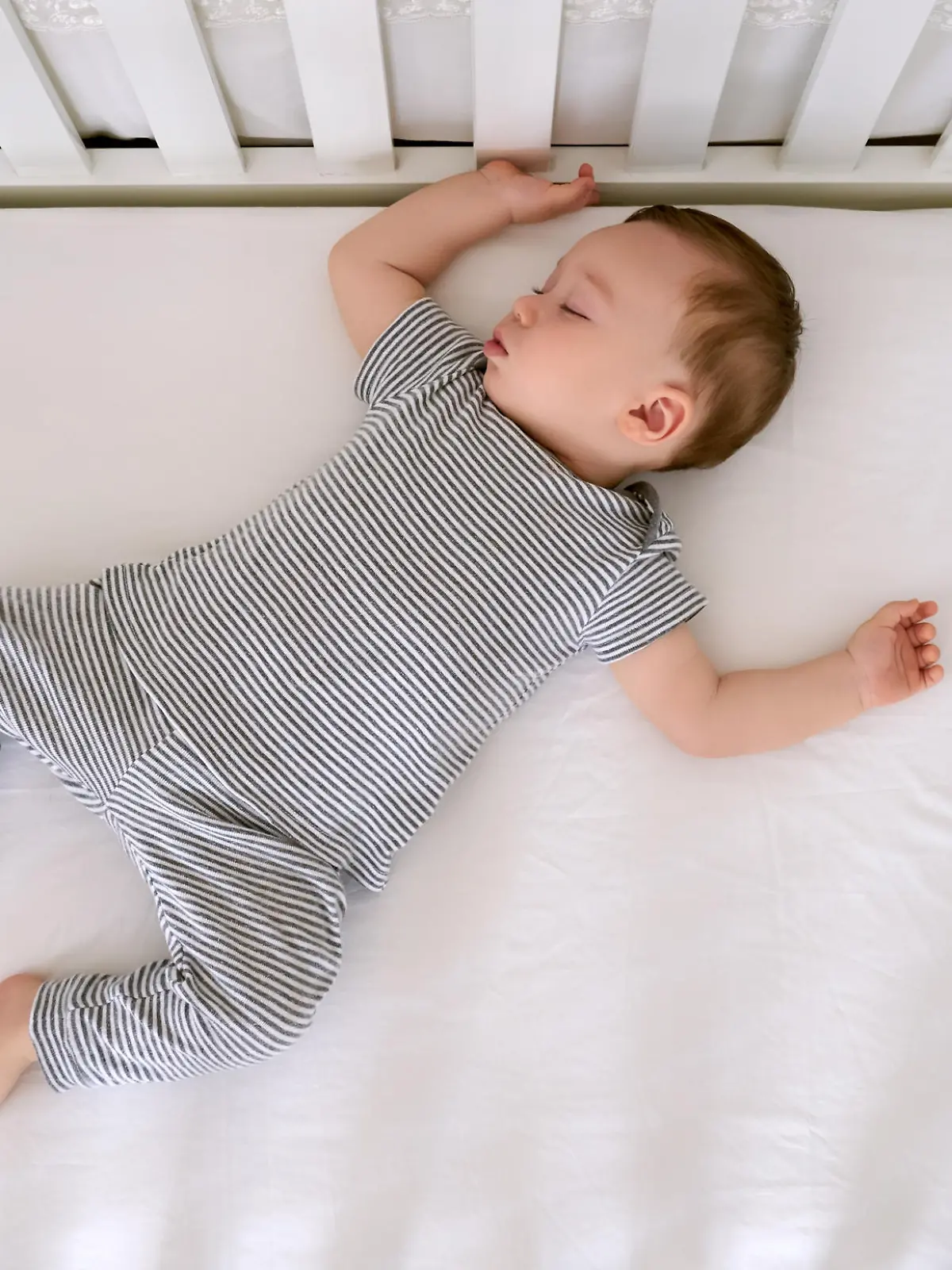 Baby schläft auf Matratze im Babybett