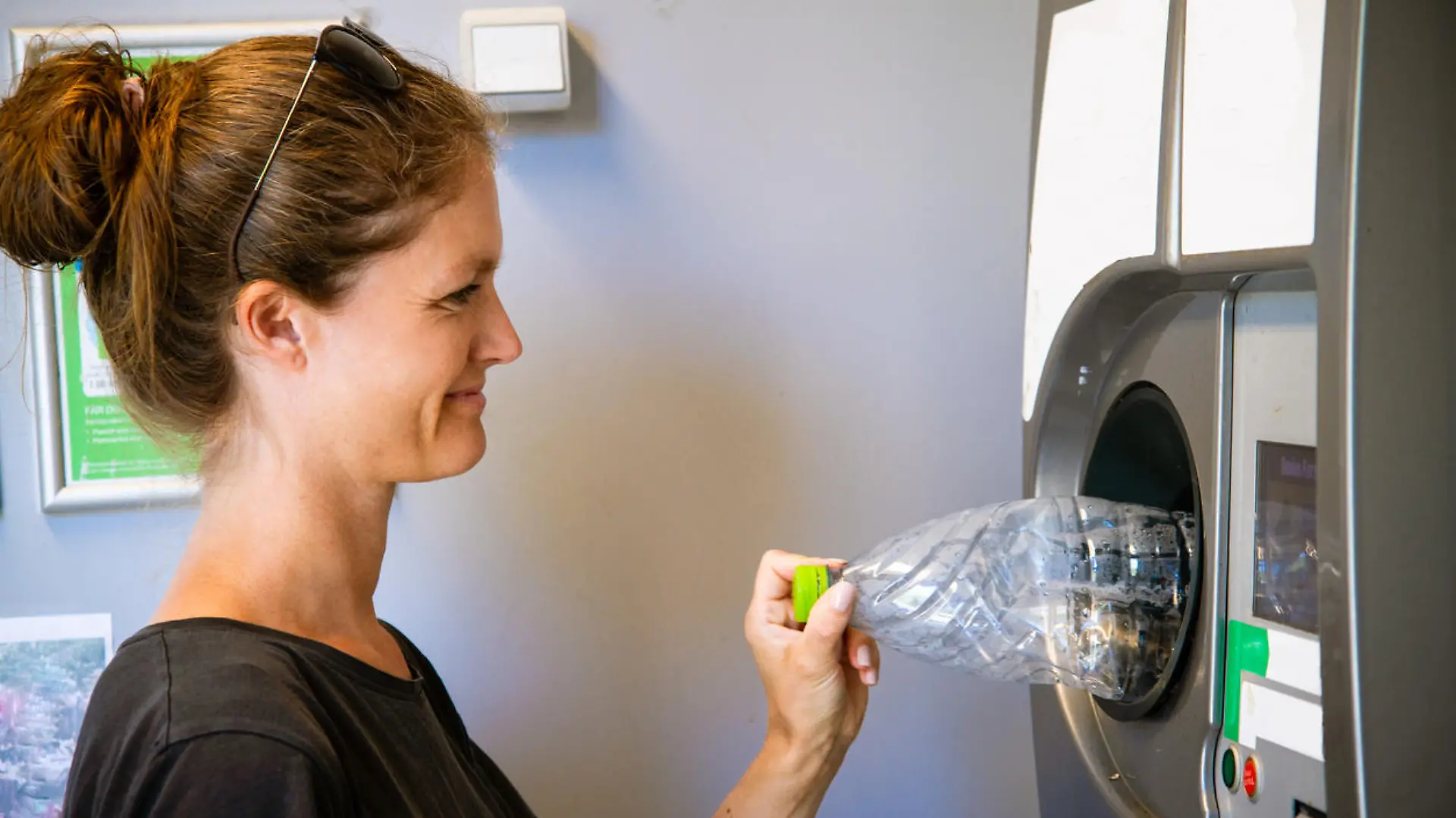 Young female recycling plastic bottle. These automatic recycling machines are found in every supermarket in Denmark. By law, every consumer pays a bottle deposit when purchasing e.g. a plastic bottle with water/soda. The deposit is then returned once the consumer returns the bottle in the supermarket again.