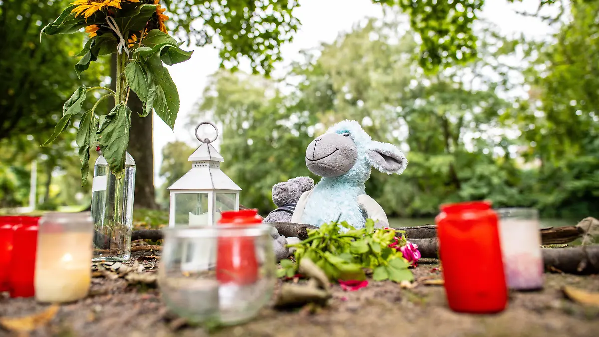 20.09.2021, Nordrhein-Westfalen, Hamm: Zwei Stofftiere, Kerzen und Sonnenblumen stehen an dem kleinen See am Oberlandesgericht, wo am Sonntag eine Frauenleiche gefunden wurde. Im Fall einer 25-Jährigen, die am Sonntag tot in einer Grünanlage in Hamm gefunden wurde, geht die Staatsanwaltschaft von einem Tötungsdelikt aus. Am Montag suchten Taucher einen kleinen See am Tatort ab, wie der Sprecher der Staatsanwaltschaft schilderte. Foto: Guido Kirchner/dpa +++ dpa-Bildfunk +++