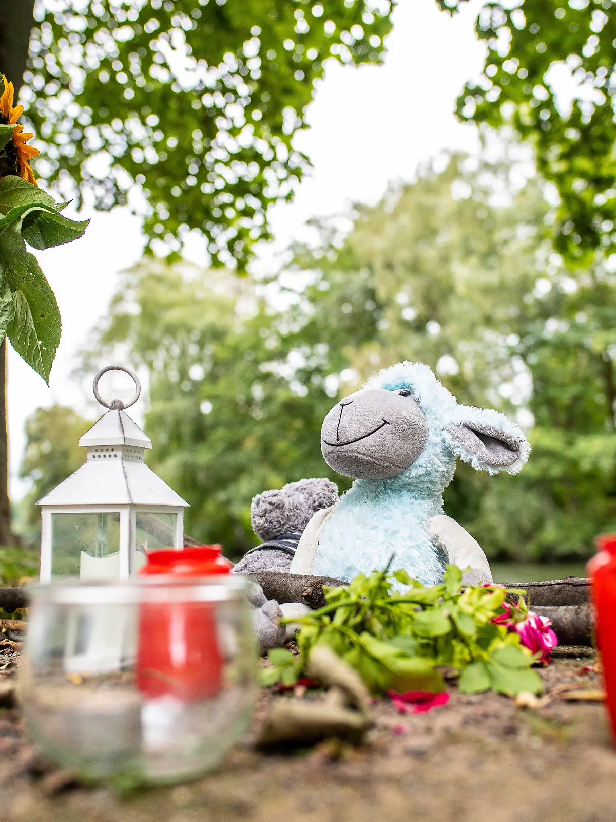 20.09.2021, Nordrhein-Westfalen, Hamm: Zwei Stofftiere, Kerzen und Sonnenblumen stehen an dem kleinen See am Oberlandesgericht, wo am Sonntag eine Frauenleiche gefunden wurde. Im Fall einer 25-Jährigen, die am Sonntag tot in einer Grünanlage in Hamm gefunden wurde, geht die Staatsanwaltschaft von einem Tötungsdelikt aus. Am Montag suchten Taucher einen kleinen See am Tatort ab, wie der Sprecher der Staatsanwaltschaft schilderte. Foto: Guido Kirchner/dpa +++ dpa-Bildfunk +++