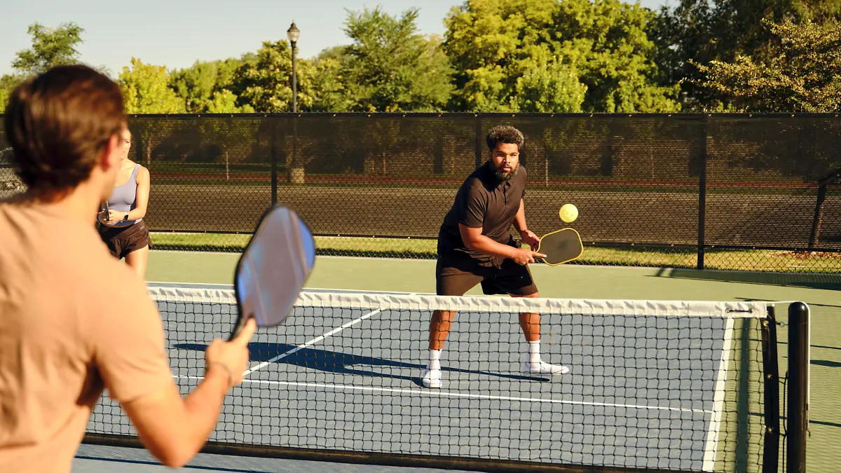 A group of young adults playing Pickleball at a public court.