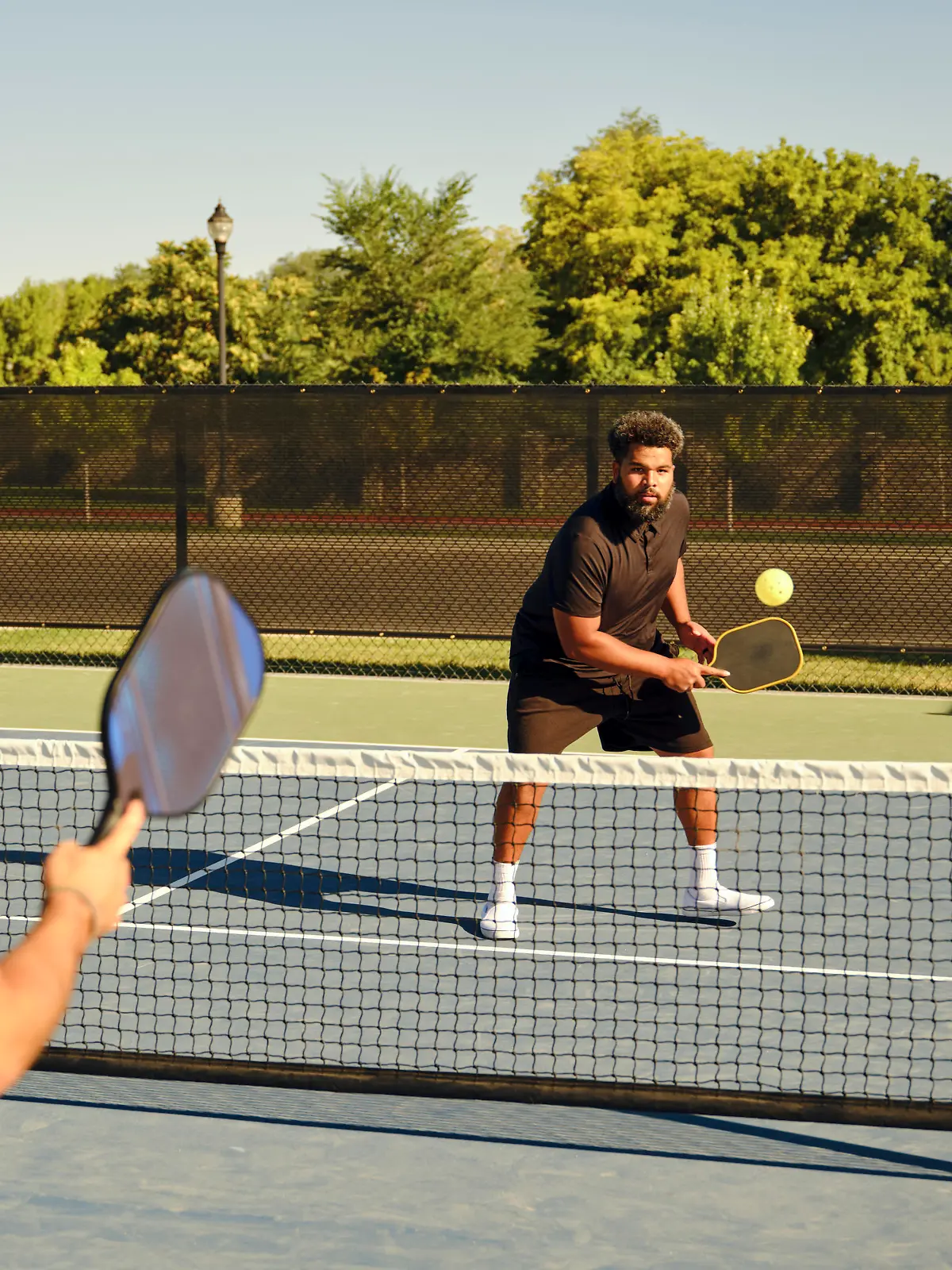A group of young adults playing Pickleball at a public court.