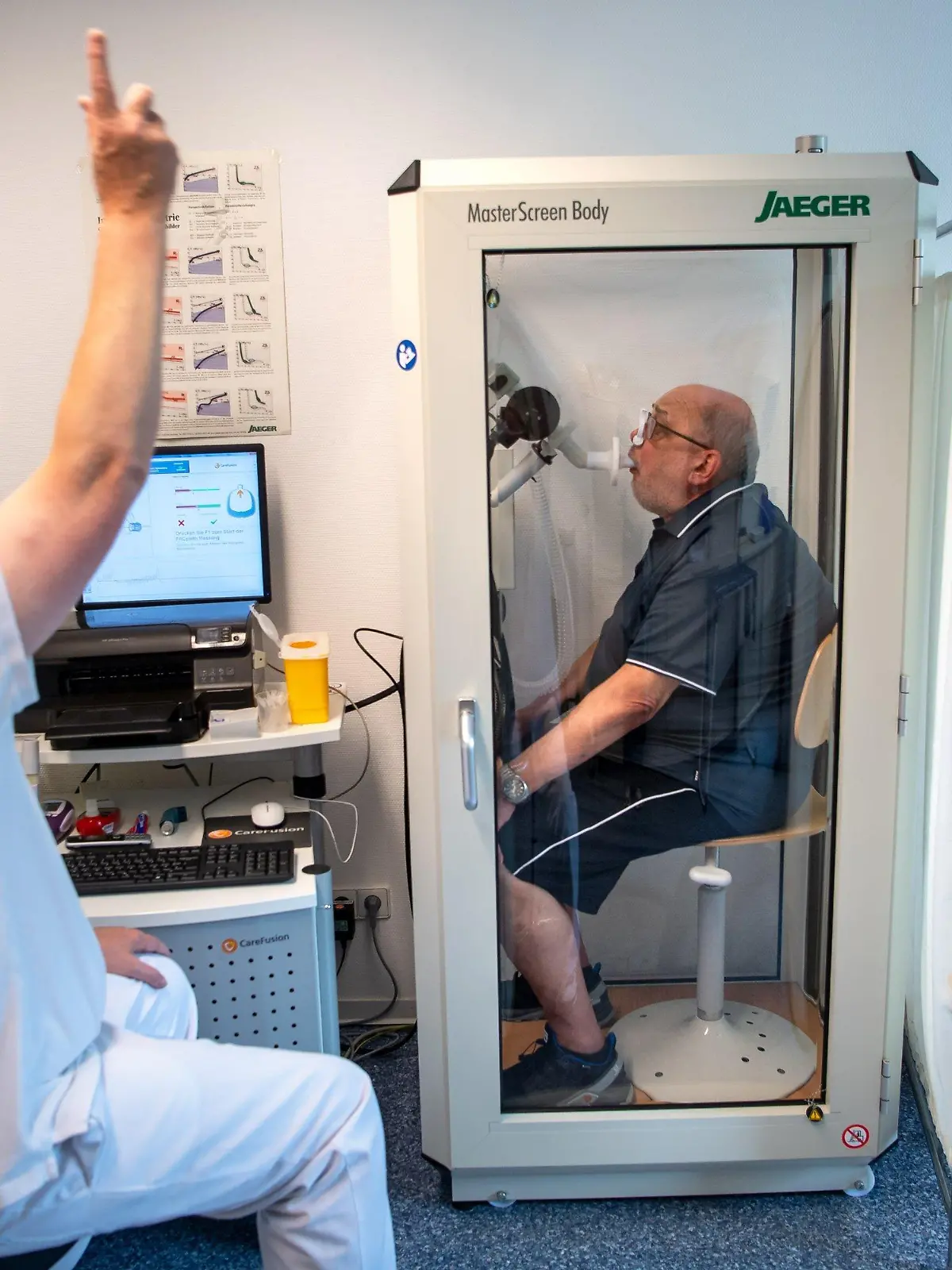 PRODUKTION - 27.07.2021, Niedersachsen, Bad Rothenfelde: Reinhard Janzen sitzt zur Überprüfung seiner Lungenfunktion in einem Bodyplethysmographen. In der Klinik am Teutoburger Wald werden Long-Covid-Patienten behandelt. (zu dpa «Aus dem Leben geworfen - Reha für Menschen mit Long Covid») Foto: Sina Schuldt/dpa +++ dpa-Bildfunk +++