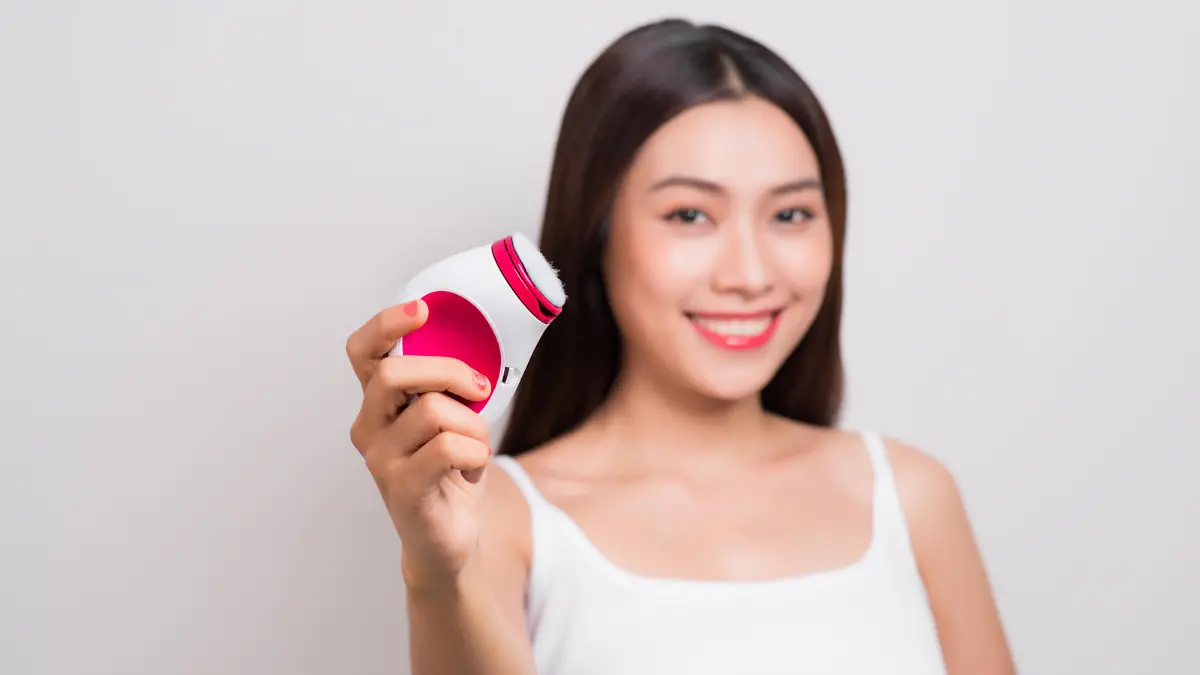 Young asian woman uses an electric brush for deeply clean