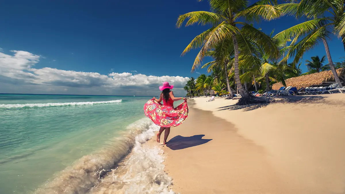 Carefree young woman walking on the tropical sandy beach, Saona island, Dominican Republic