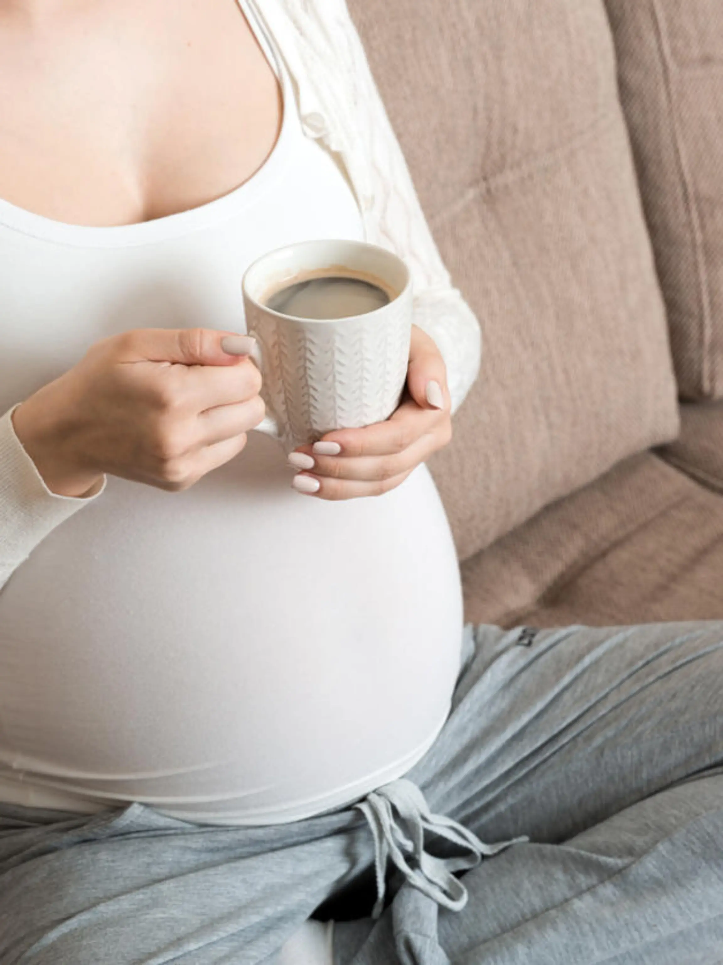 pregnant girl sitting on sofa with coffee Cup in hand coffee. maternity morning.