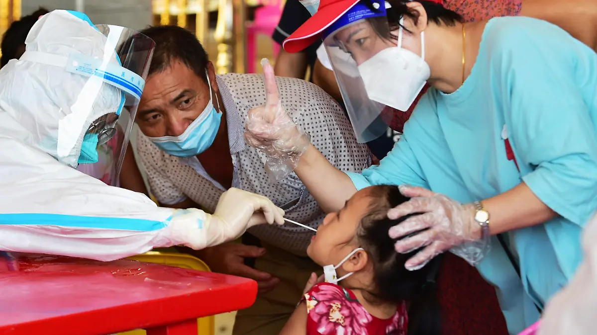 In this photo released by Xinhua News Agency, a health worker collects swab sample from a girl for nucleic acid testing in Xianyou county, Putian city, southeastern China's Fujian Province Thursday, Sept. 16, 2021. China has reported another 62 cases of COVID-19, even as the number of Chinese citizens fully vaccinated has topped 1 billion. (Wei Peiquan/Xinhua via AP)
