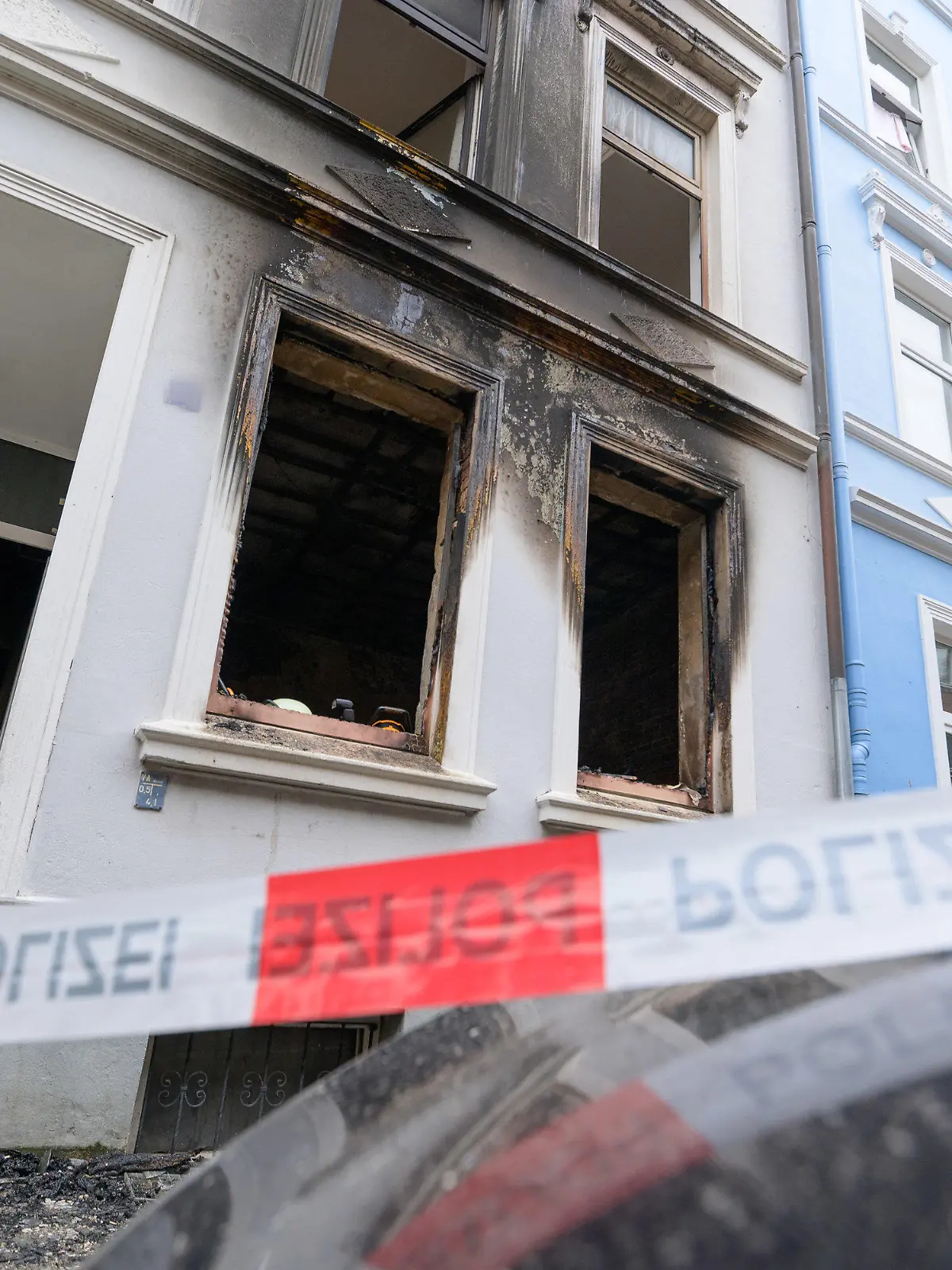 19.09.2021, Hamburg: Ein Polizist betritt den Hauseingang neben der Brandwohnung. Bei einem Wohnungsbrand in Hamburg-Harburg sind am frühen Sonntagmorgen zwei Menschen ums Leben gekommen. Eine weitere Person sei lebensgefährlich verletzt worden, sagte ein Sprecher der Feuerwehr. Foto: Jonas Walzberg/dpa - ACHTUNG: Person(en) wurde(n) aus rechtlichen Gründen gepixelt +++ dpa-Bildfunk +++