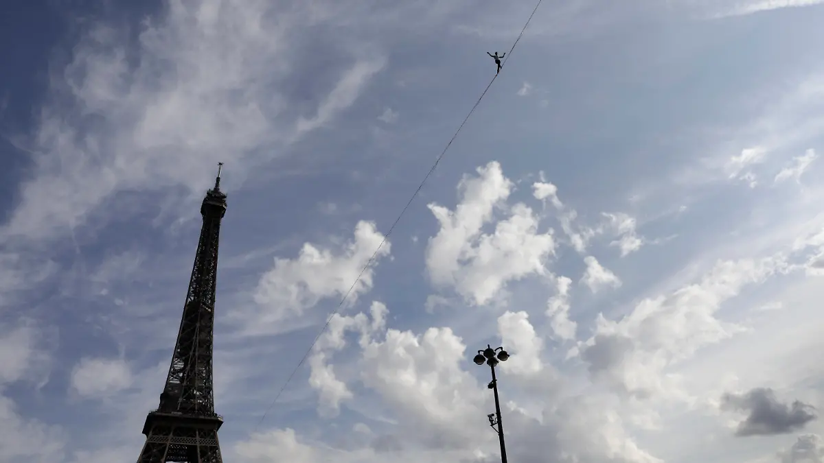 18.09.2021, Frankreich, Paris: Nathan Paulin, Akrobat aus Frankreich, versucht, auf einem Seil vom Eiffelturm über die Seine zu laufen. Das Kunstück ist Teil der Veranstaltungen in ganz Frankreich anlässlich der Tage des nationalen Kulturerbes. Foto: Lewis Joly/AP/dpa +++ dpa-Bildfunk +++