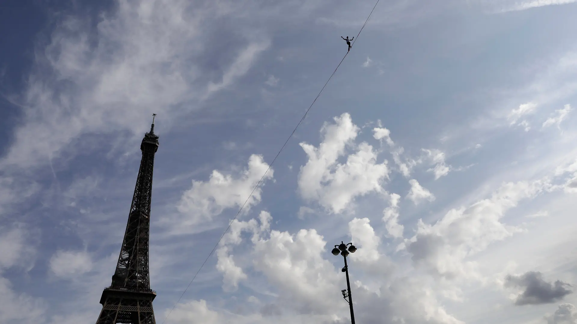 18.09.2021, Frankreich, Paris: Nathan Paulin, Akrobat aus Frankreich, versucht, auf einem Seil vom Eiffelturm über die Seine zu laufen. Das Kunstück ist Teil der Veranstaltungen in ganz Frankreich anlässlich der Tage des nationalen Kulturerbes. Foto: Lewis Joly/AP/dpa +++ dpa-Bildfunk +++
