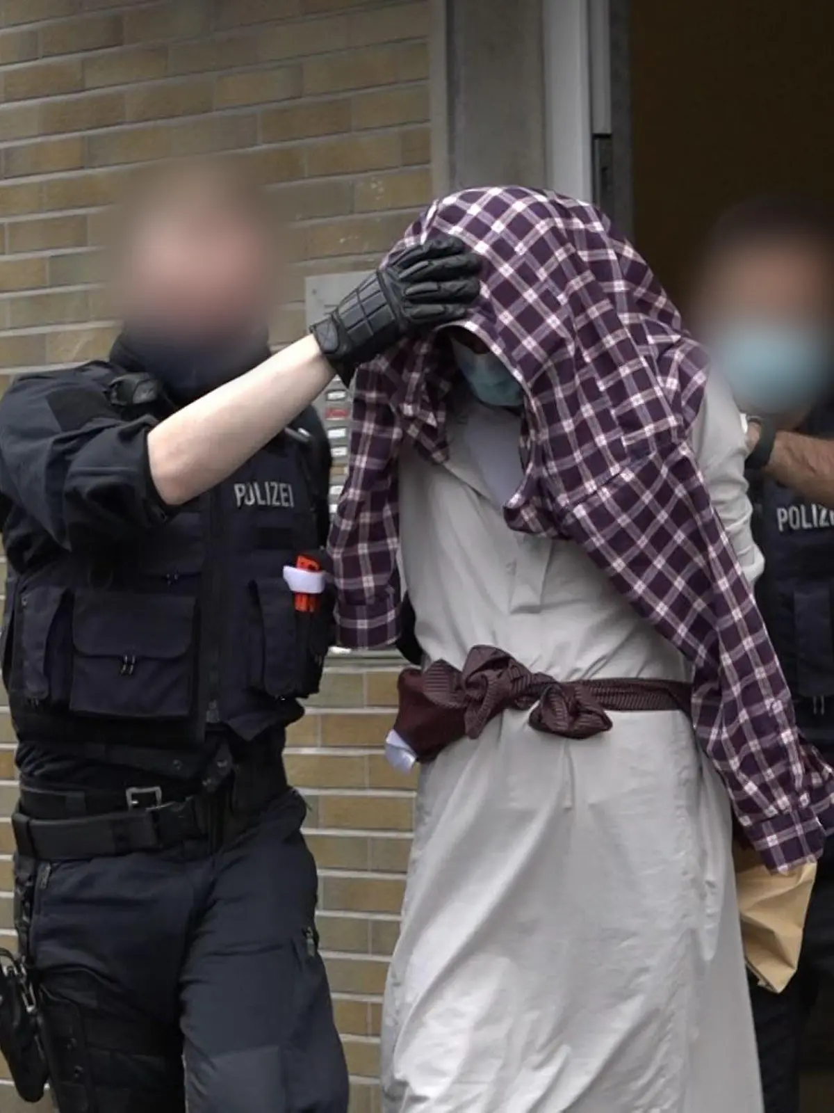 dpatopbilder - 16.09.2021, Nordrhein-Westfalen, Hagen: Ein Mann wird im Zusammenhang mit dem mutmaßlich geplanten Anschlag auf die Hagener Synagoge von Polizisten abgeführt. Nach dem Polizeieinsatz an der Synagoge in Hagen hat die Polizei vier Verdächtige festgenommen, darunter einen 16-Jährigen in Hagen. Das teilte die Hagener Polizei am Donnerstag mit. Parallel liefen Durchsuchungen, um mögliche Beweismittel zu sichern, sagte ein Sprecherin. Foto: Alex Talash/dpa - ACHTUNG: Personen wurden aus rechtlichen Gründen gepixelt +++ dpa-Bildfunk +++