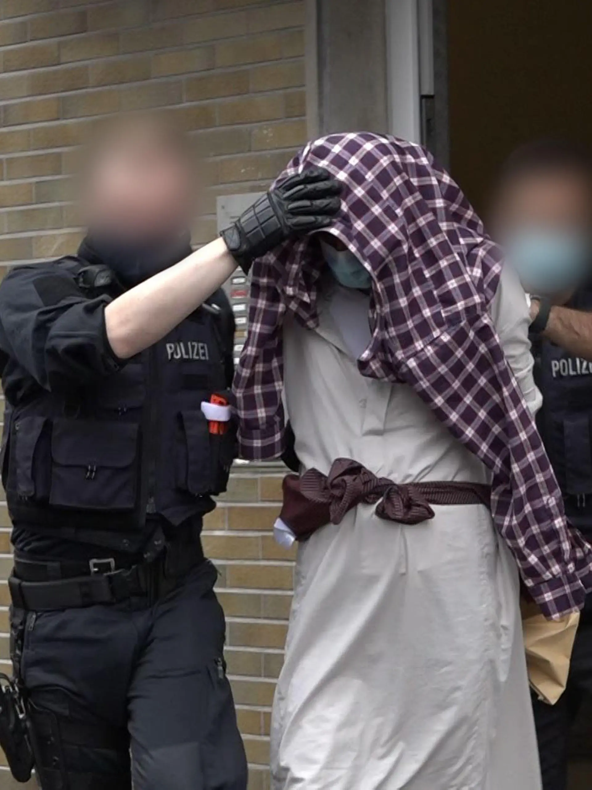 dpatopbilder - 16.09.2021, Nordrhein-Westfalen, Hagen: Ein Mann wird im Zusammenhang mit dem mutmaßlich geplanten Anschlag auf die Hagener Synagoge von Polizisten abgeführt. Nach dem Polizeieinsatz an der Synagoge in Hagen hat die Polizei vier Verdächtige festgenommen, darunter einen 16-Jährigen in Hagen. Das teilte die Hagener Polizei am Donnerstag mit. Parallel liefen Durchsuchungen, um mögliche Beweismittel zu sichern, sagte ein Sprecherin. Foto: Alex Talash/dpa - ACHTUNG: Personen wurden aus rechtlichen Gründen gepixelt +++ dpa-Bildfunk +++