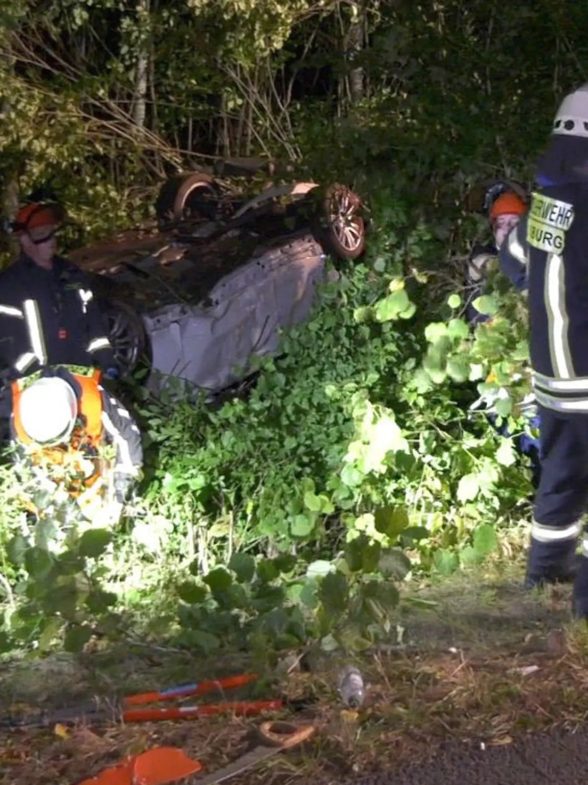17.09.2021, Hessen, Groß-Zimmern: Feuerwehrleute arbeiten an  einem Auto abseits der Straße. Auf der Bundesstraße 26 bei Groß-Zimmern (Kreis Darmstadt-Dieburg) hat sich am Donnerstagabend ein 18 Jahre alter Autofahrer mit seinem Wagen überschlagen. Dabei seien der Fahrer und seine vier Mitfahrer im Alter zwischen 18 und 20 Jahren verletzt worden, teilte die Polizei am Freitag mit. Foto: -/KEUTZ TV-NEWS/dpa +++ dpa-Bildfunk +++
