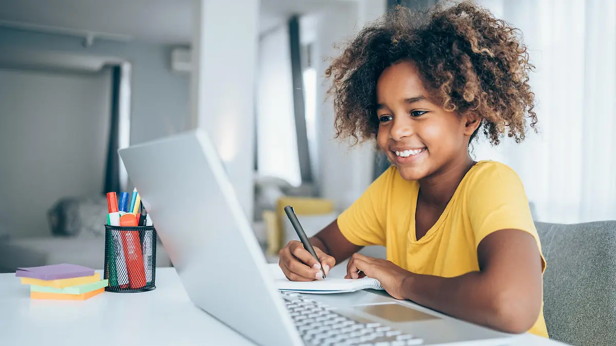 Young student watching lesson online and studying from home. Girl using laptop for online lessons. Homeschooling and distance learning concept.