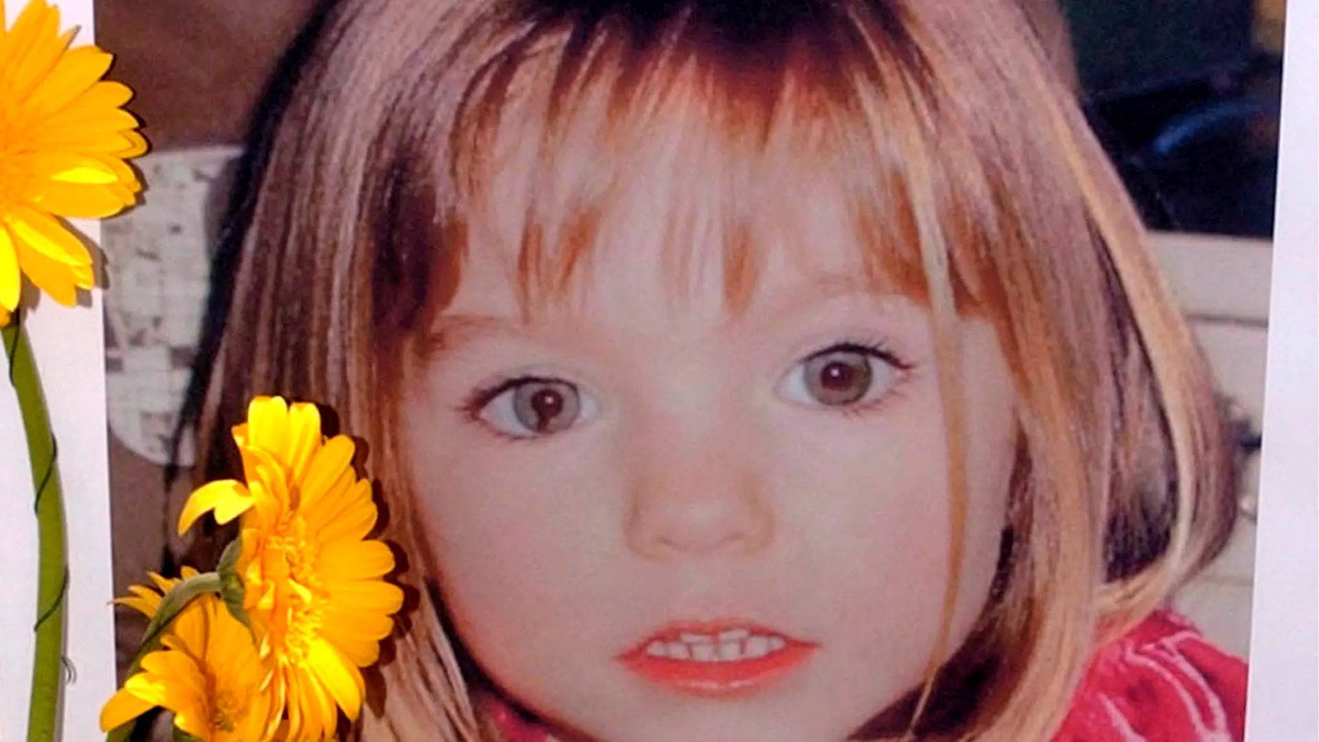 ARCHIV - 12.05.2007, Portugal, Lagos: Blumen stehen vor einem Bild, das die verschwundene Madeleine McCann (Maddie) auf einem Foto zeigt, das ihre Eltern im Zusammenhang mit dem Verschwinden des Kindes veröffentlich haben. Am 3. Mai 2007 verschwand die damals Dreijährige aus Großbritannien aus einem Ferienappartement im portugiesischen Praia da Luz. (zu dpa "Anklage wegen Sexualstraftaten gegen Verdächtigen im Fall Maddie") Foto: Luis Forra/LUSA/epa/dpa +++ dpa-Bildfunk +++