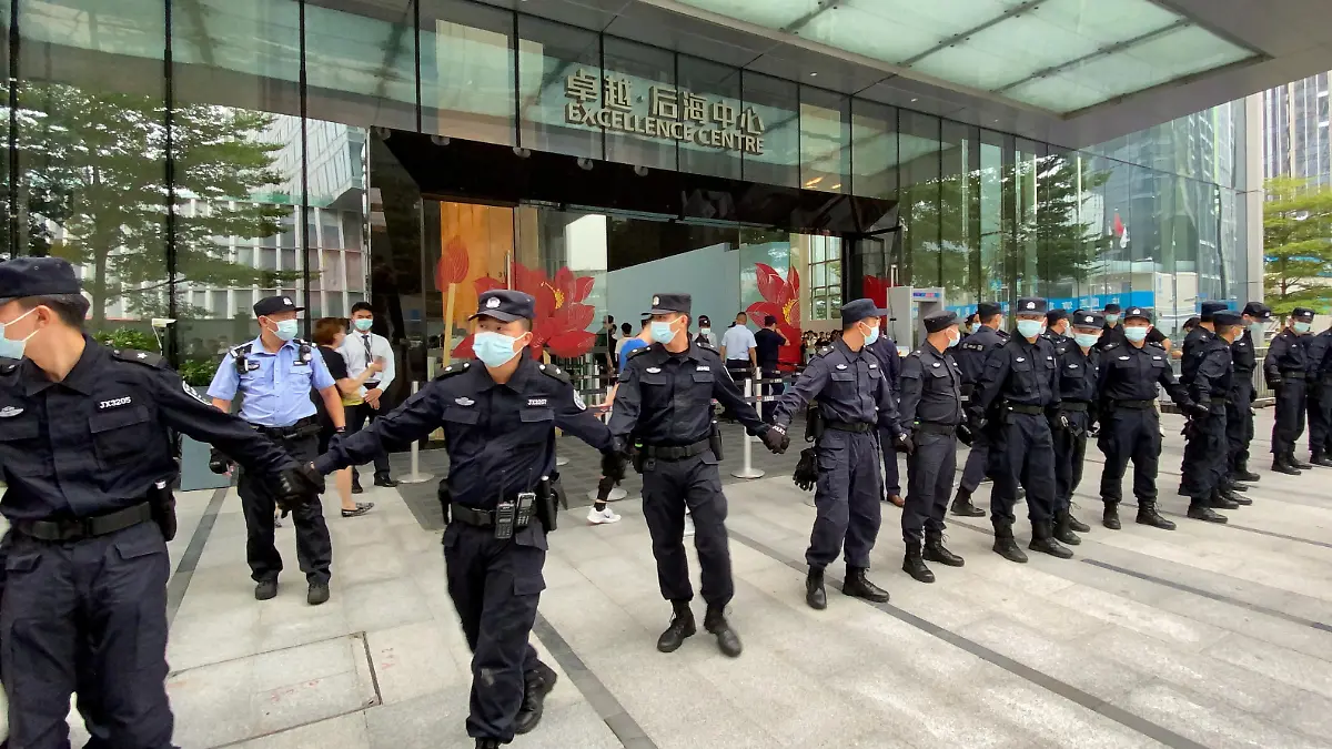 FILE PHOTO: Security personnel form a human chain as they guard outside the Evergrande's headquarters, where people gathered to demand repayment of loans and financial products, in Shenzhen, Guangdong province, China September 13, 2021. REUTERS/David Kirton/File Photo