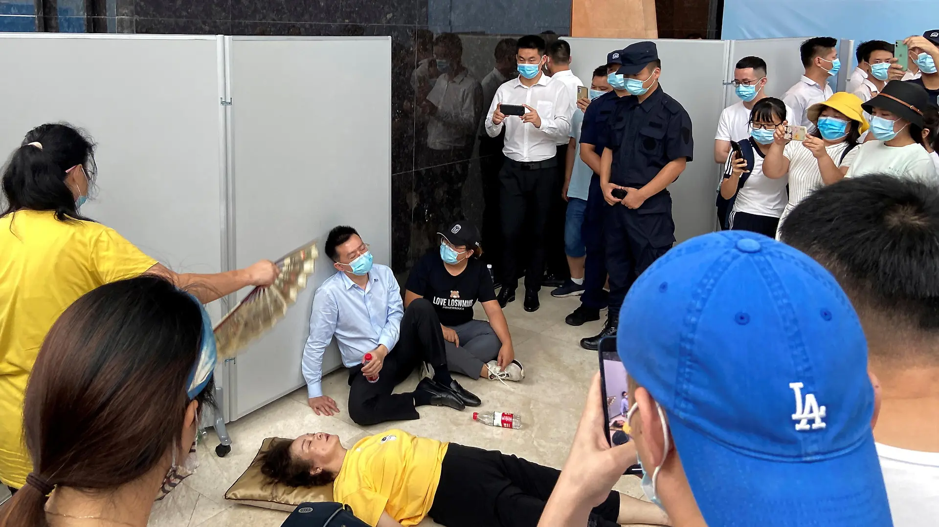 A woman receives aid on the ground next to Du Liang, general manager and legal representative of Evergrande's wealth management division, while people gather to demand repayment of loans and financial products at the Evergrande's headquarters, in Shenzhen, Guangdong province, China September 13, 2021. REUTERS/David Kirton REFILE- CORRECTING NAME