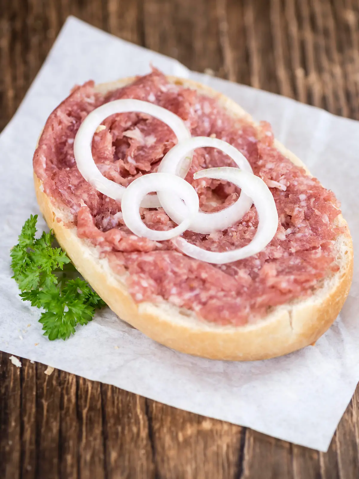 German Cuisine (bun with Mett; selective focus) on wooden background (detailed close-up shot)