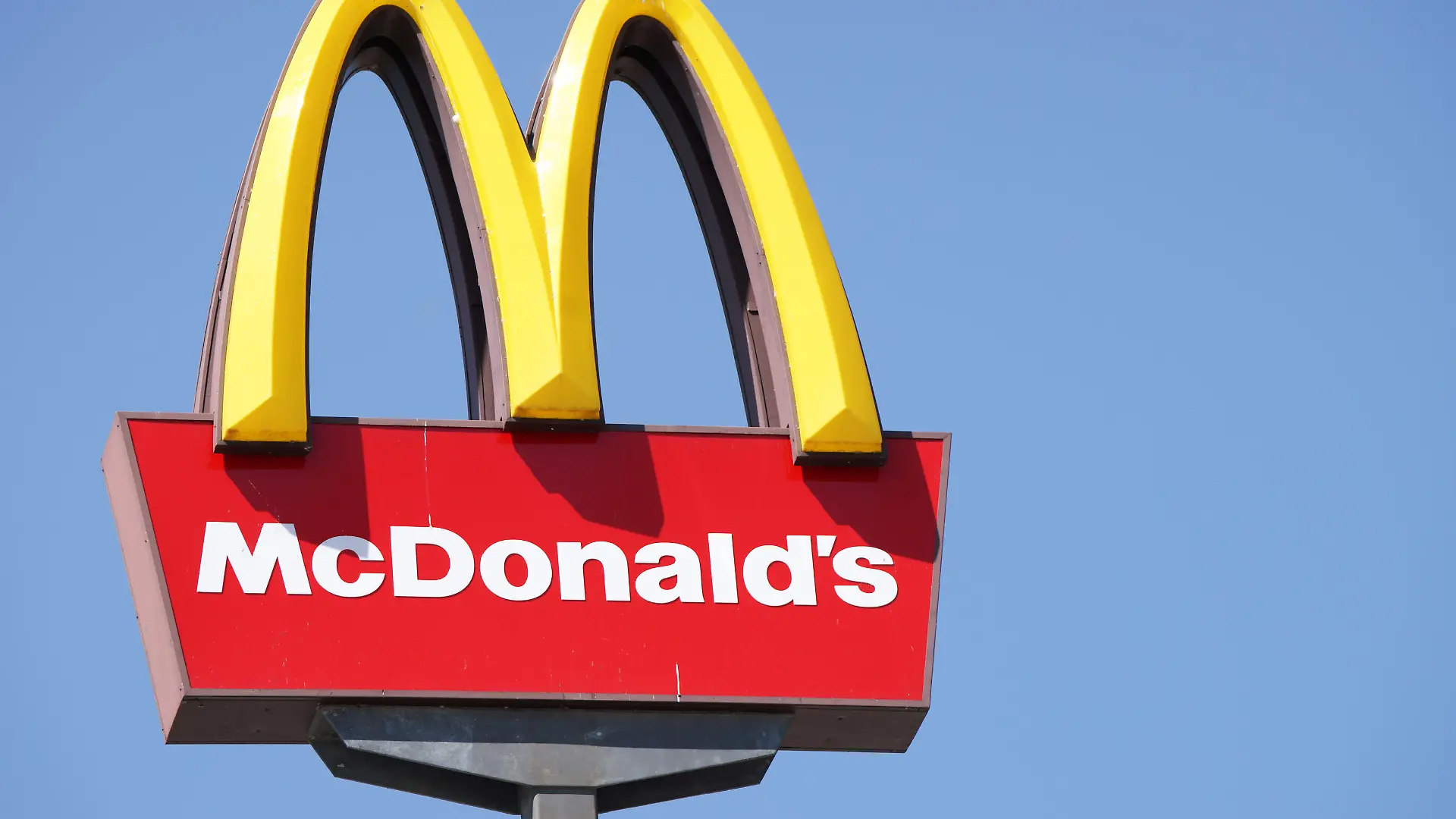 Ljubljana, Slovenia - September 3, 2011: Close-up of McDonalds outdoor sign with typical rounded yellow M letter against cloudless blue sky. Sign is positioned on the left side of image.