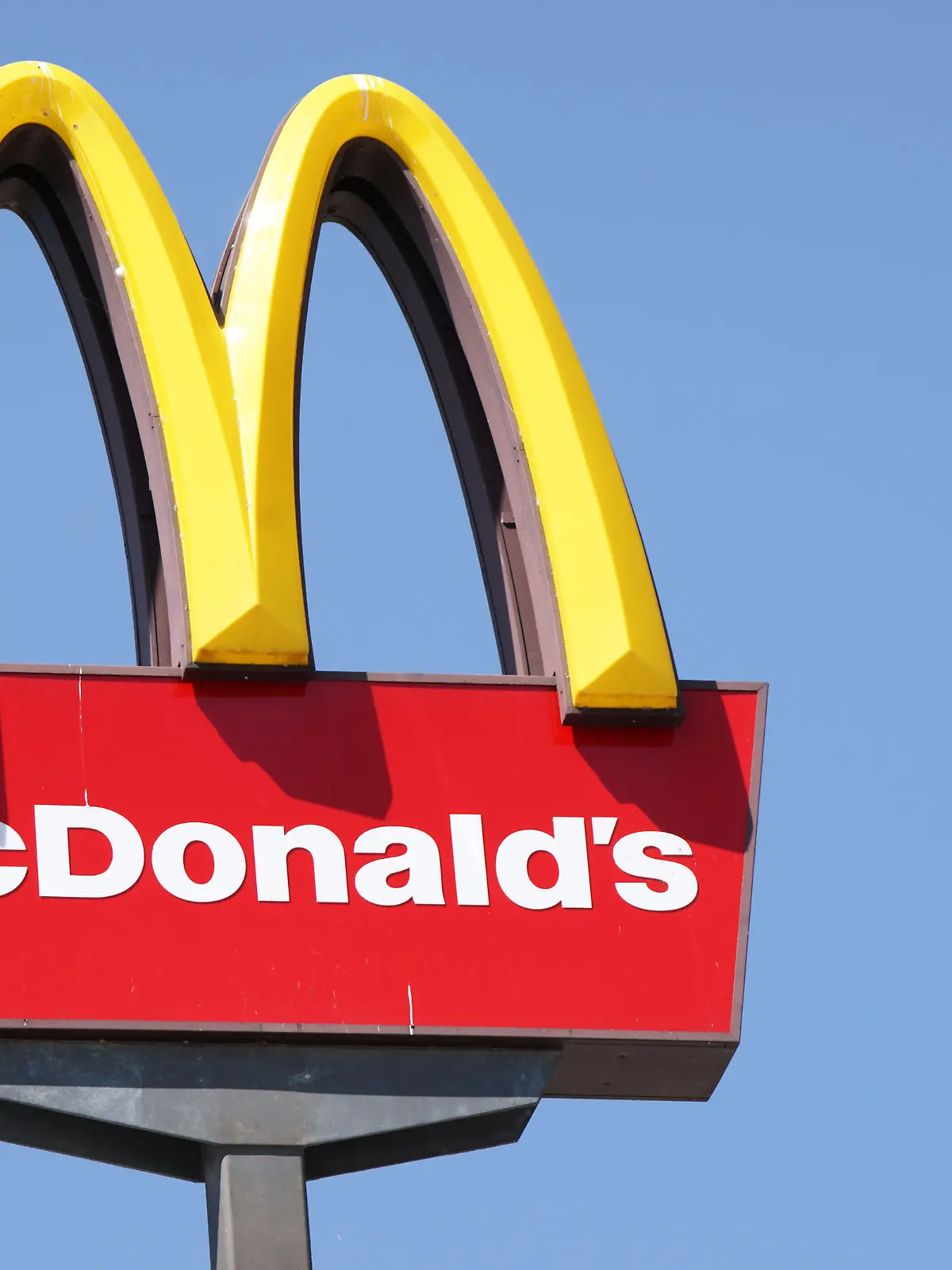 Ljubljana, Slovenia - September 3, 2011: Close-up of McDonalds outdoor sign with  typical rounded yellow M letter against cloudless blue sky. Sign is positioned on the left side of image.