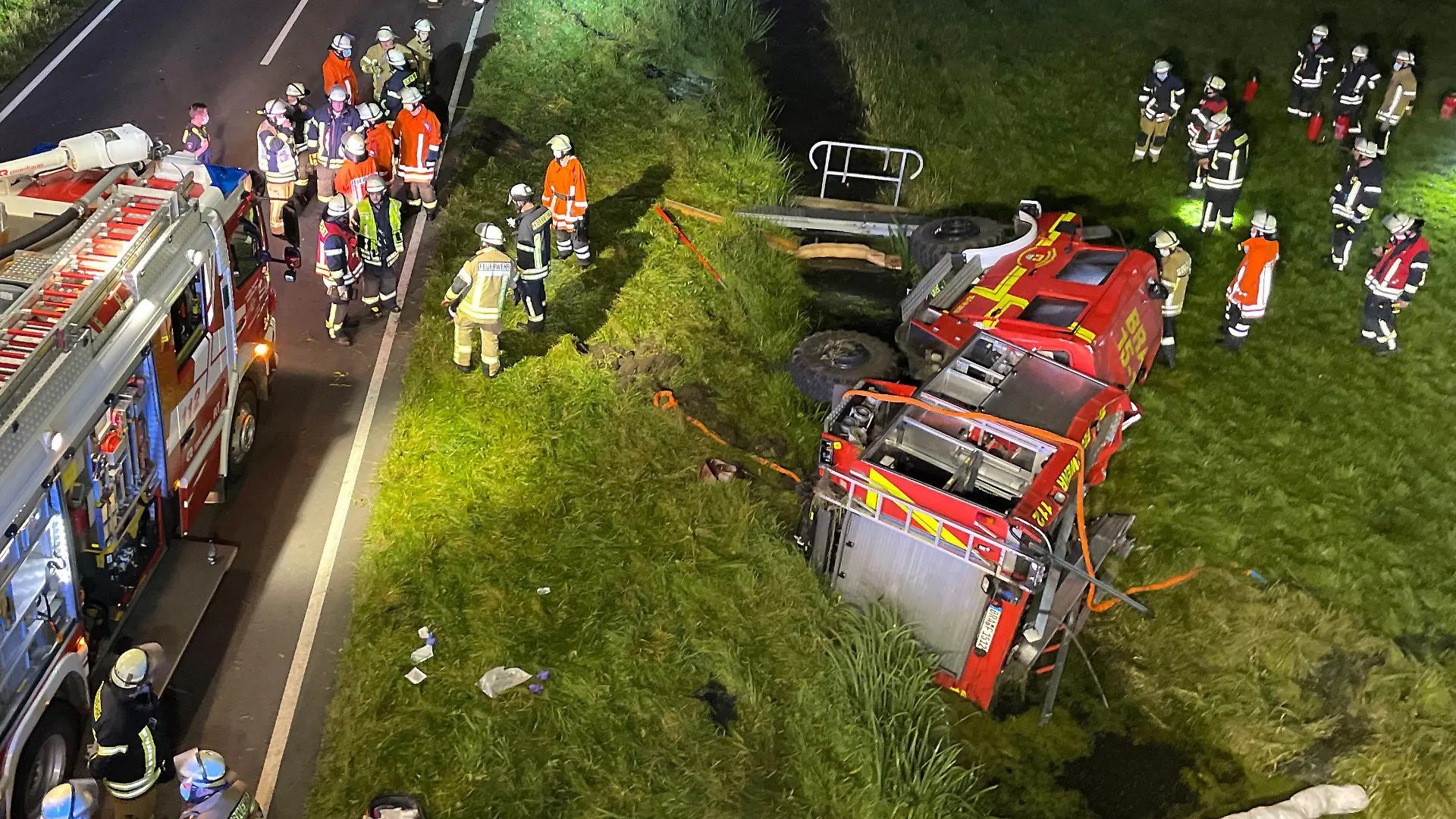 13.09.2021, Niedersachsen, Brake: Feuerwehrleute stehen um ein verunfalltes Einsatzfahrzeug auf der B212 bei Brake (Unterweser). Sechs Feuerwehrleute sind bei einem Unfall mit ihrem Tanklöschfahrzeug kurz vor Brake verletzt worden. Die Feuerwehrleute waren unterwegs zu einer Übung in der Feuerwehrtechnischen Zentrale als mutmaßlich ein Reifen platzte. Foto: Andre van Elten/dpa +++ dpa-Bildfunk +++