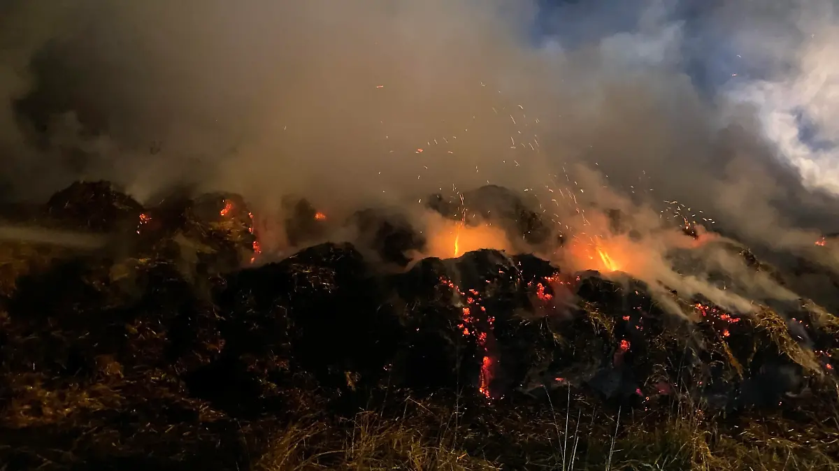 Feuerwehrleute löschen brennende Strohballen
