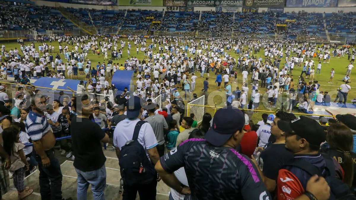Fans take to the field of Cuscatlan stadium in San Salvador, El Salvador, Saturday, May 20, 2023. At least nine people were killed and dozens more injured when stampeding fans pushed through one of the access gates at a quarterfinal Salvadoran league soccer match between Alianza and FAS. (AP Photo/Milton Flores)