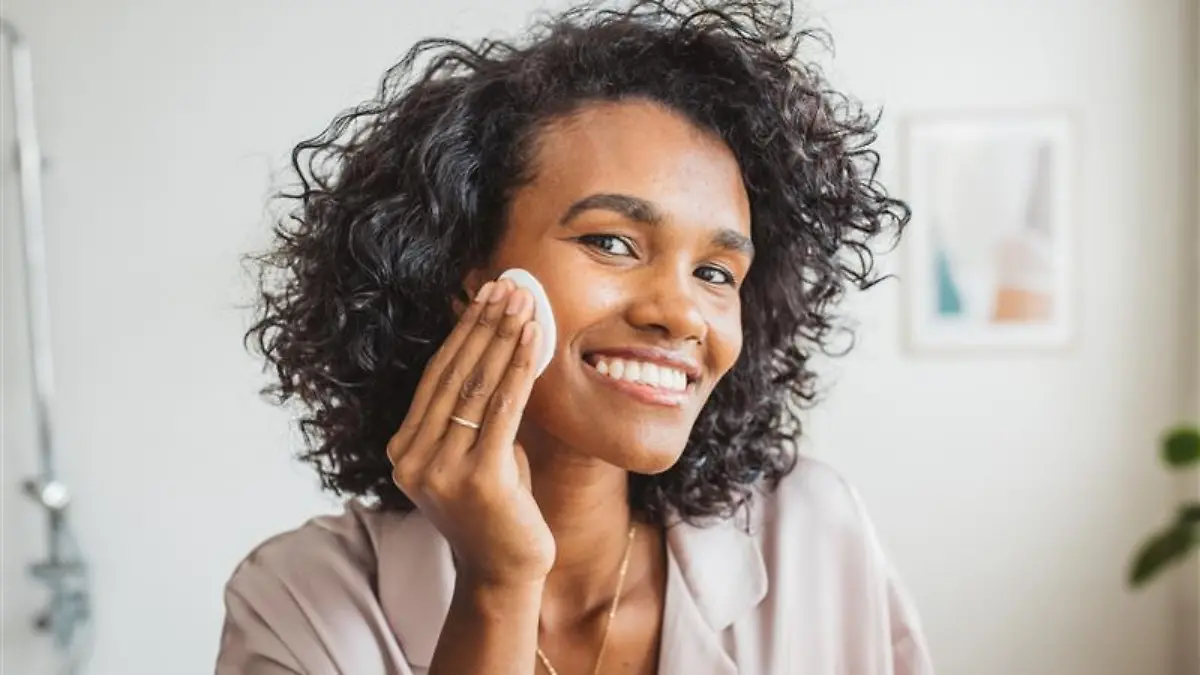 Frau trägt Toner mit BHA auf das Gesicht auf.