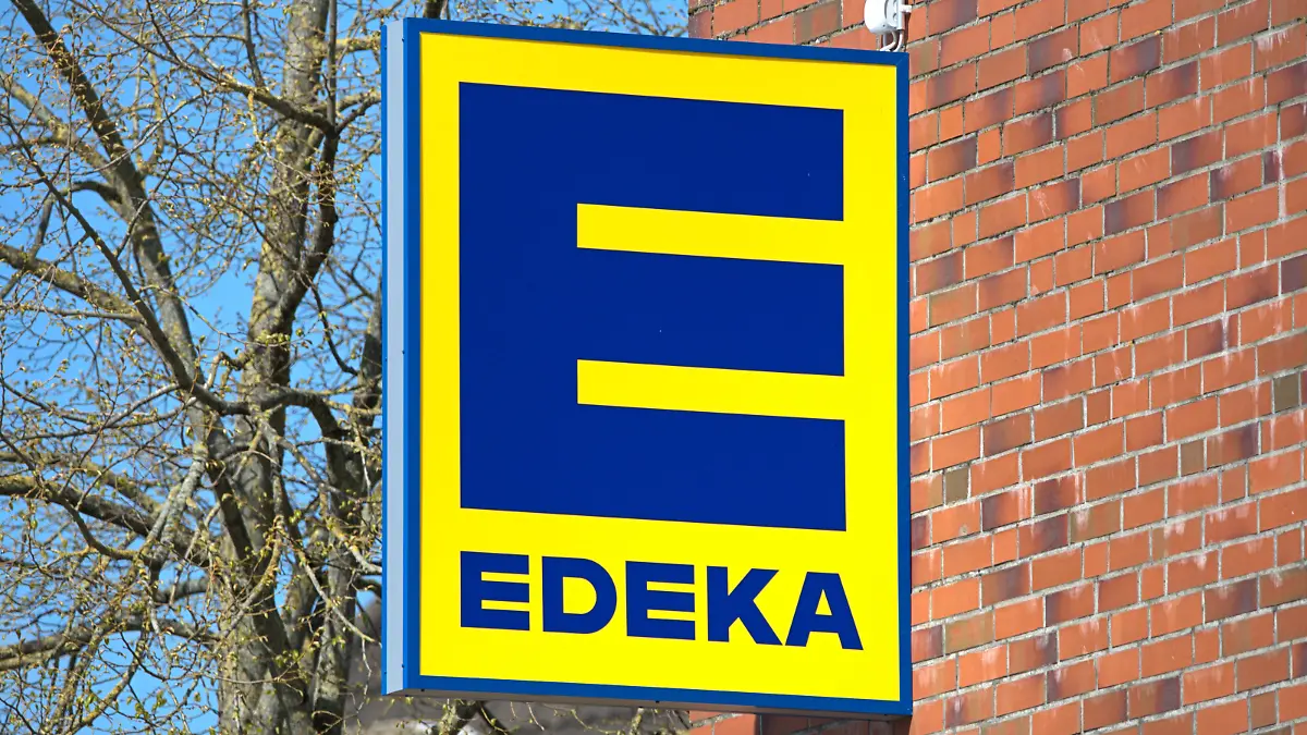 Schleswig, das Firmenschild eines Schleswiger EDEKA-Marktes an der roten Klinker-Fassade des Schlei-Centers. Die gelbe Leuchtreklame mit blauer Schrift der Handelskette bei schönem Frühlingswetter. Ein Großteil der Märkte der Edeka-Gruppe ist Inhabergeführt, die Edeka Zentrale Stiftung & Co. KG ist ein genossenschaftlich organisierter kooperativer Unternehmensverbund.