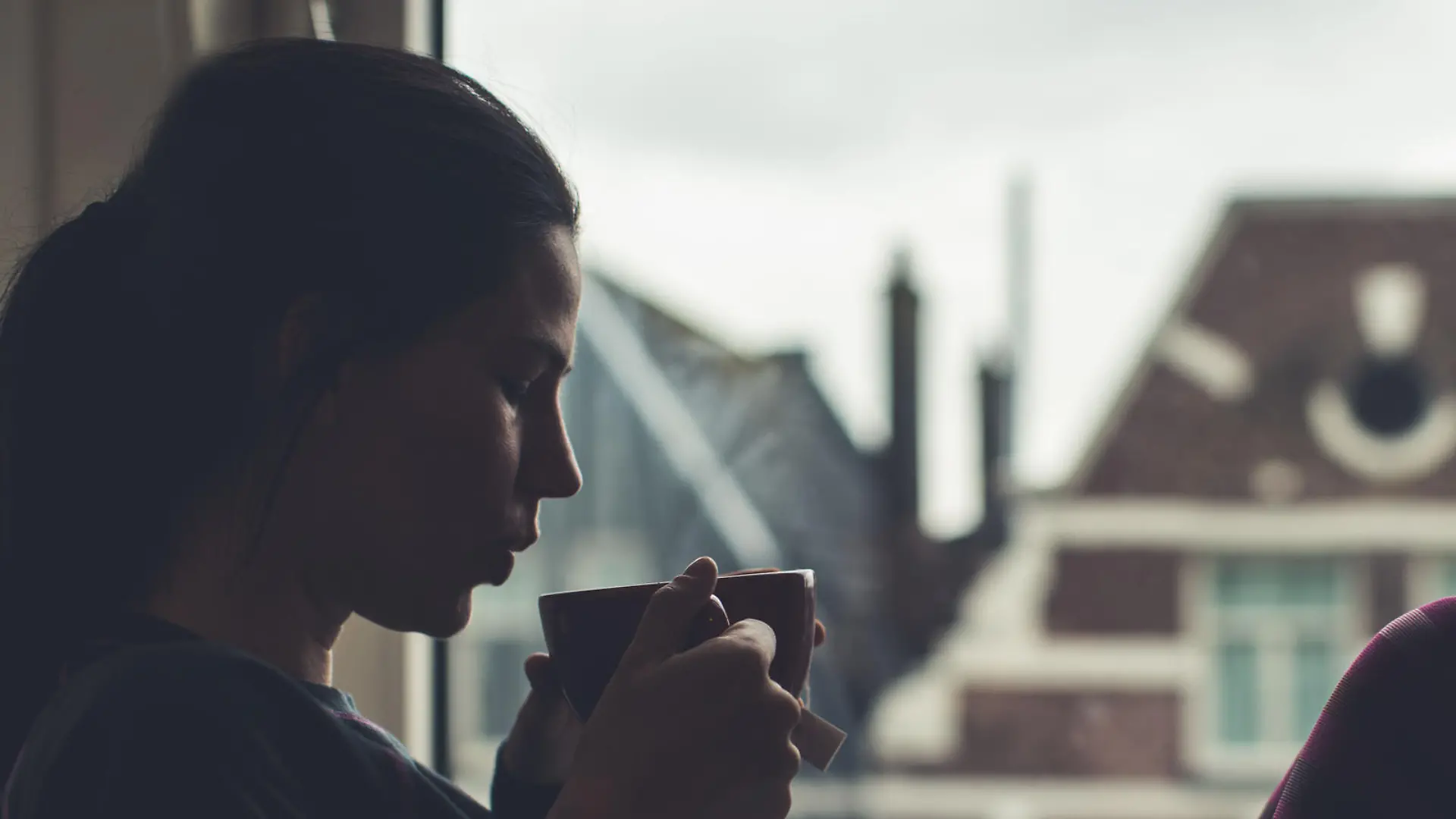 Woman drinking tea next to the window