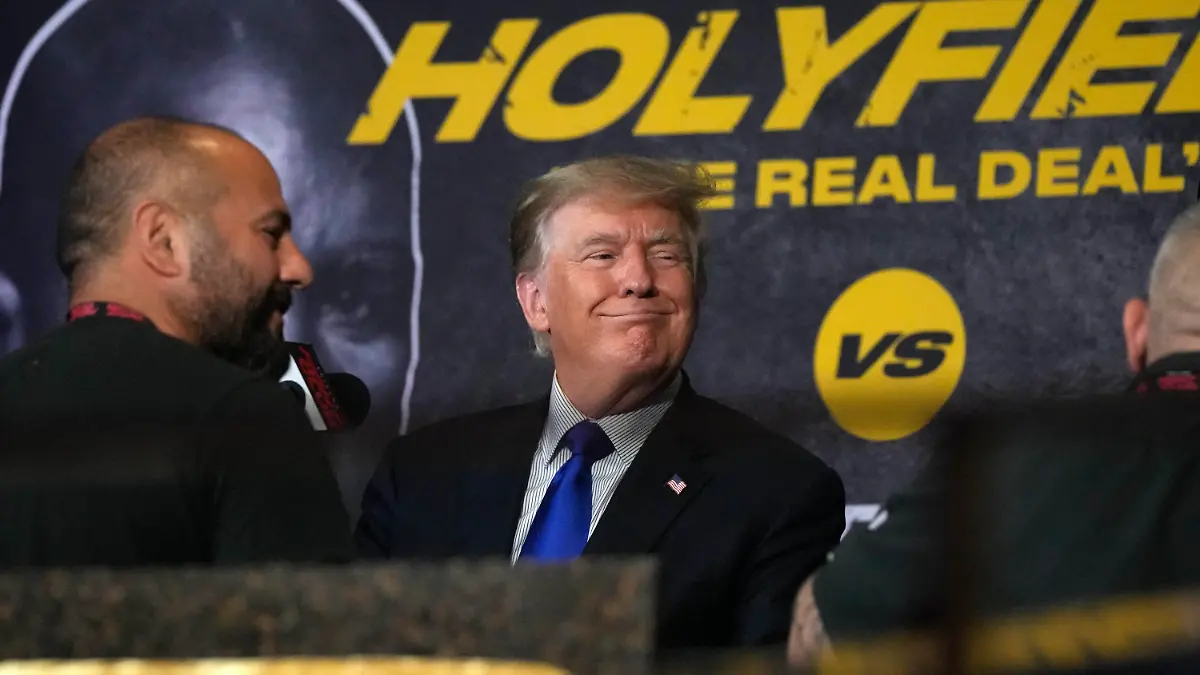 11.09.2021, USA, Hollywood: Der ehemalige US-Präsident Donald Trump (M) lächelt für ein Foto mit Anhängern, während er und sein Sohn Donald Trump Jr. (l) sich darauf vorbereiten, eine Boxveranstaltung zu kommentieren, die von einem Kampf zwischen dem ehemaligen Schwergewichtschampion Evander Holyfield und dem ehemaligen MMA-Star Vitor Belfort angeführt wird. Foto: Rebecca Blackwell/AP/dpa +++ dpa-Bildfunk +++