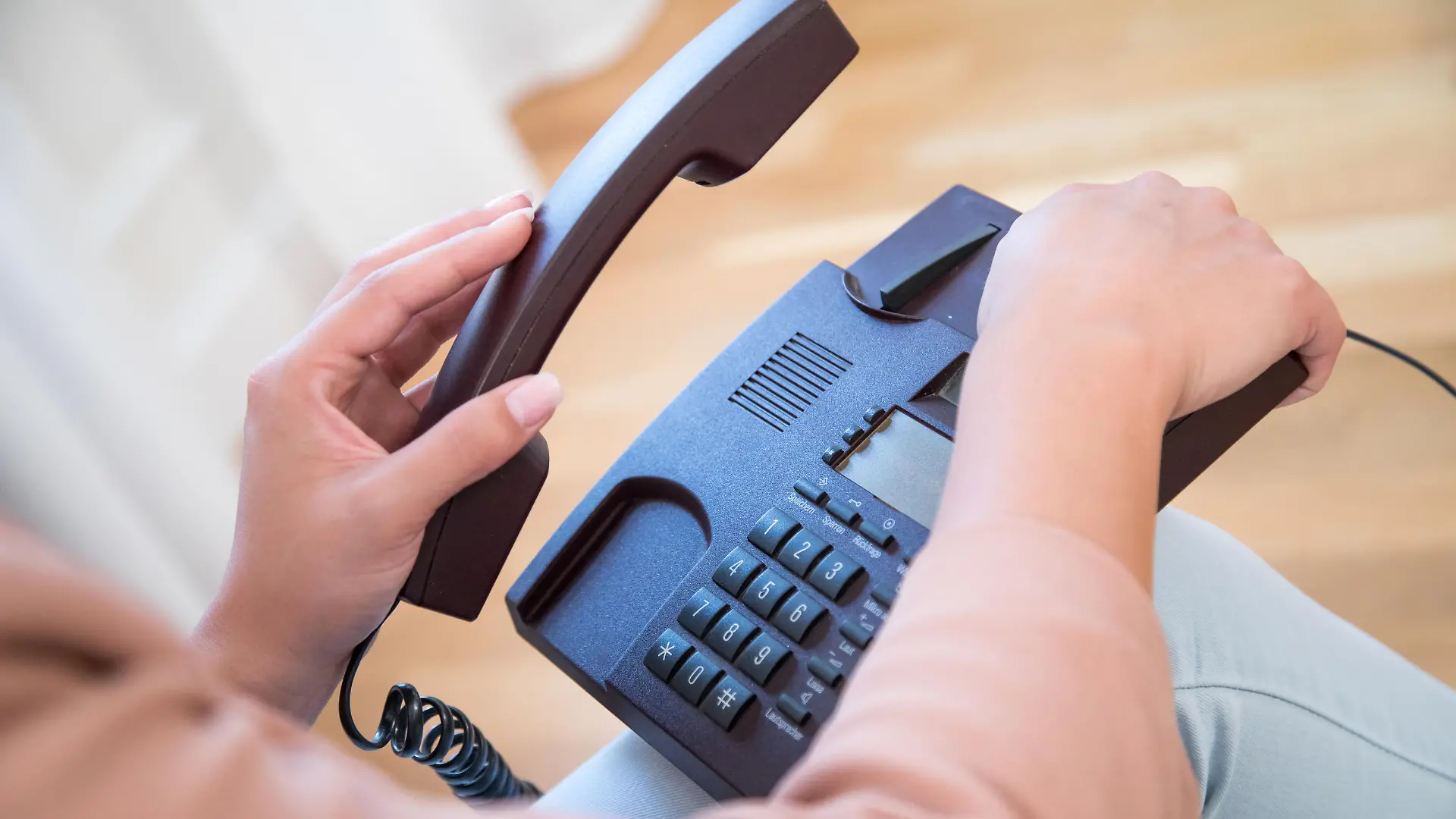 ILLUSTRATION - Eine junge Frau nimmt am 18.07.2017 in einer Wohnung in Hamburg ein Festnetz-Telefon in die Hand (gestellte Szene). Foto: Christin Klose | Verwendung weltweit