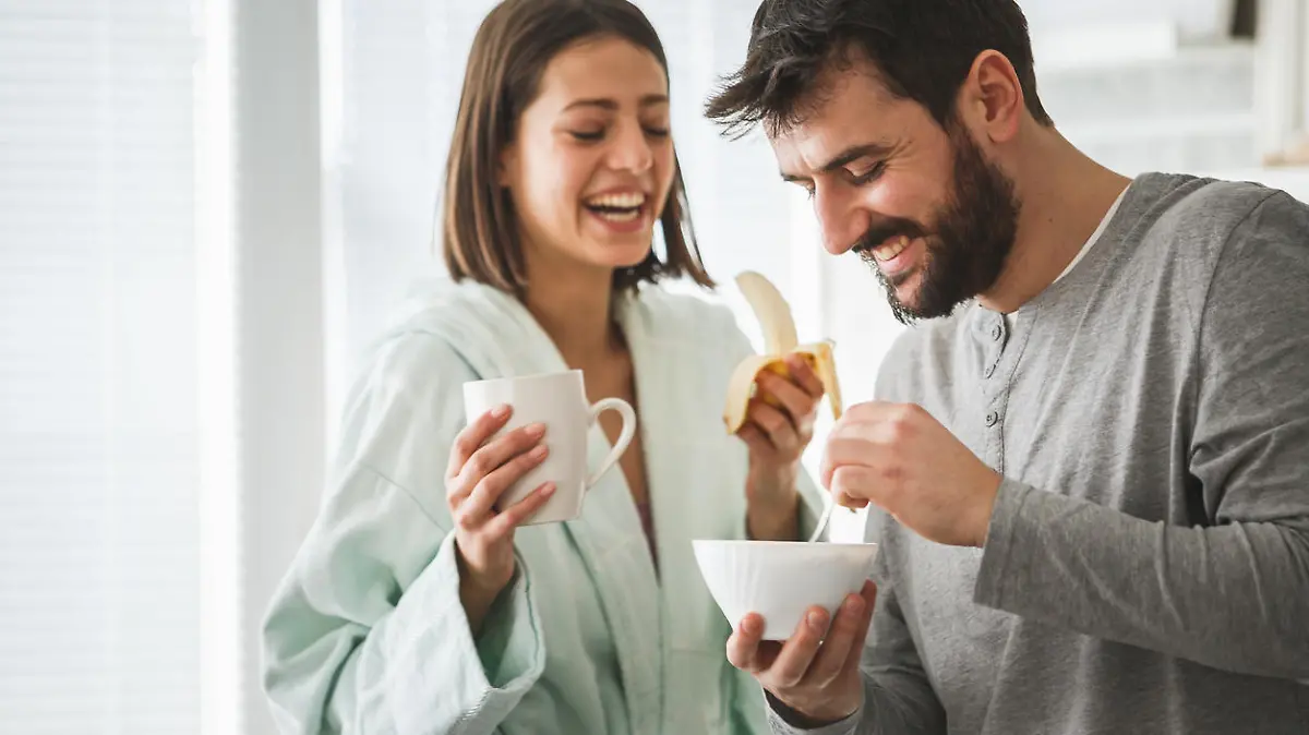 Young man and his wife are having fruit and cereals for breakfast.