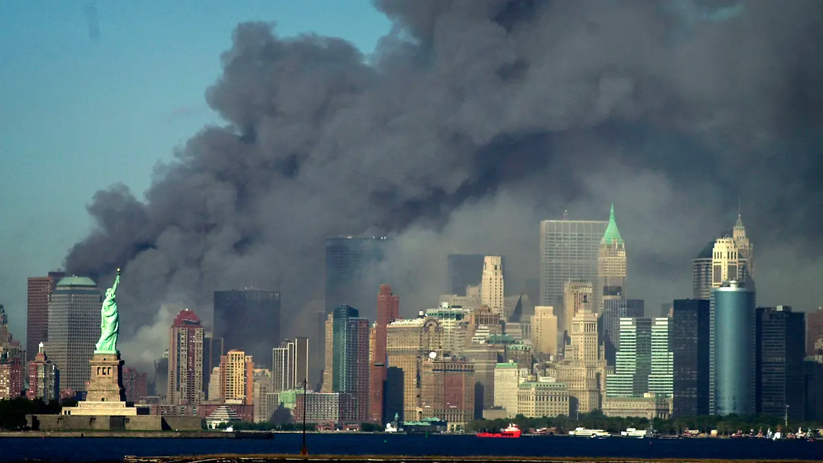 Thick smoke billows into the sky from the area behind the Statue of Liberty, lower left, where the World Trade Center was, on Tuesday, Sept. 11, 2001. (AP Photo/Daniel Hulshizer)