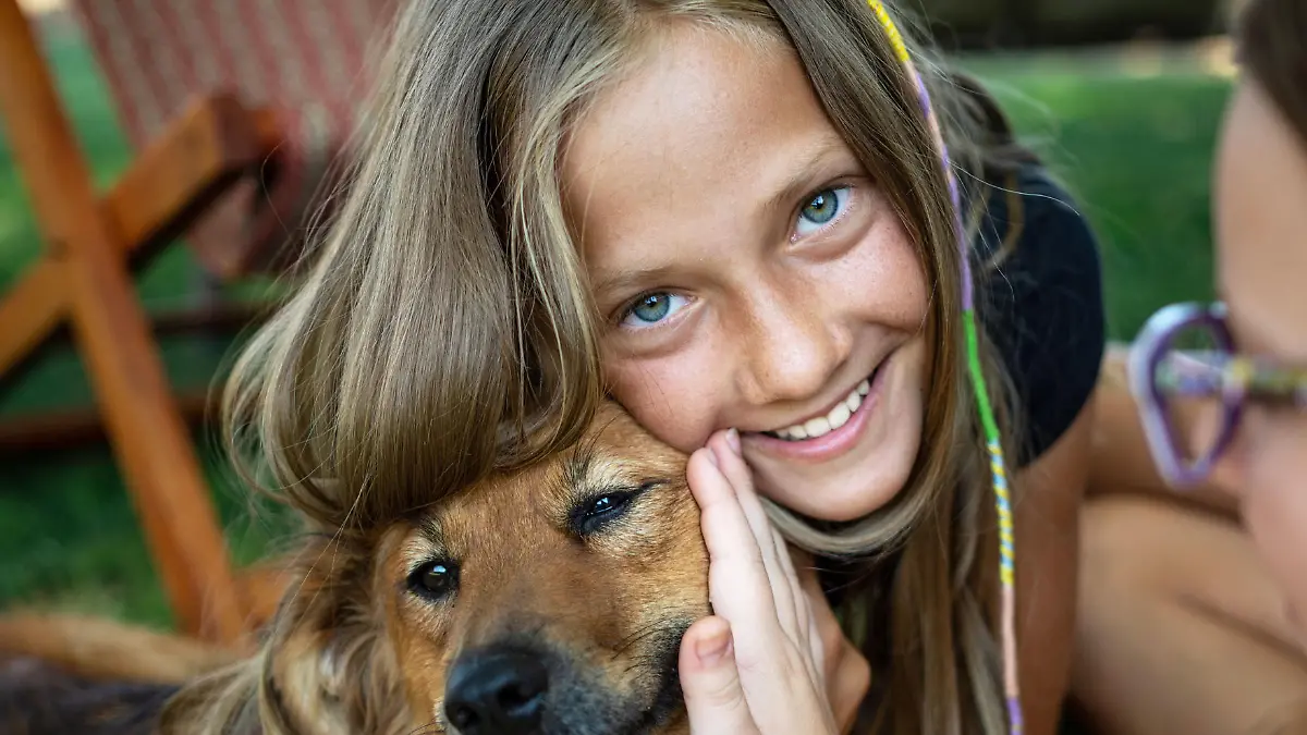 Twin sister teenage girl playing with dog in backyard