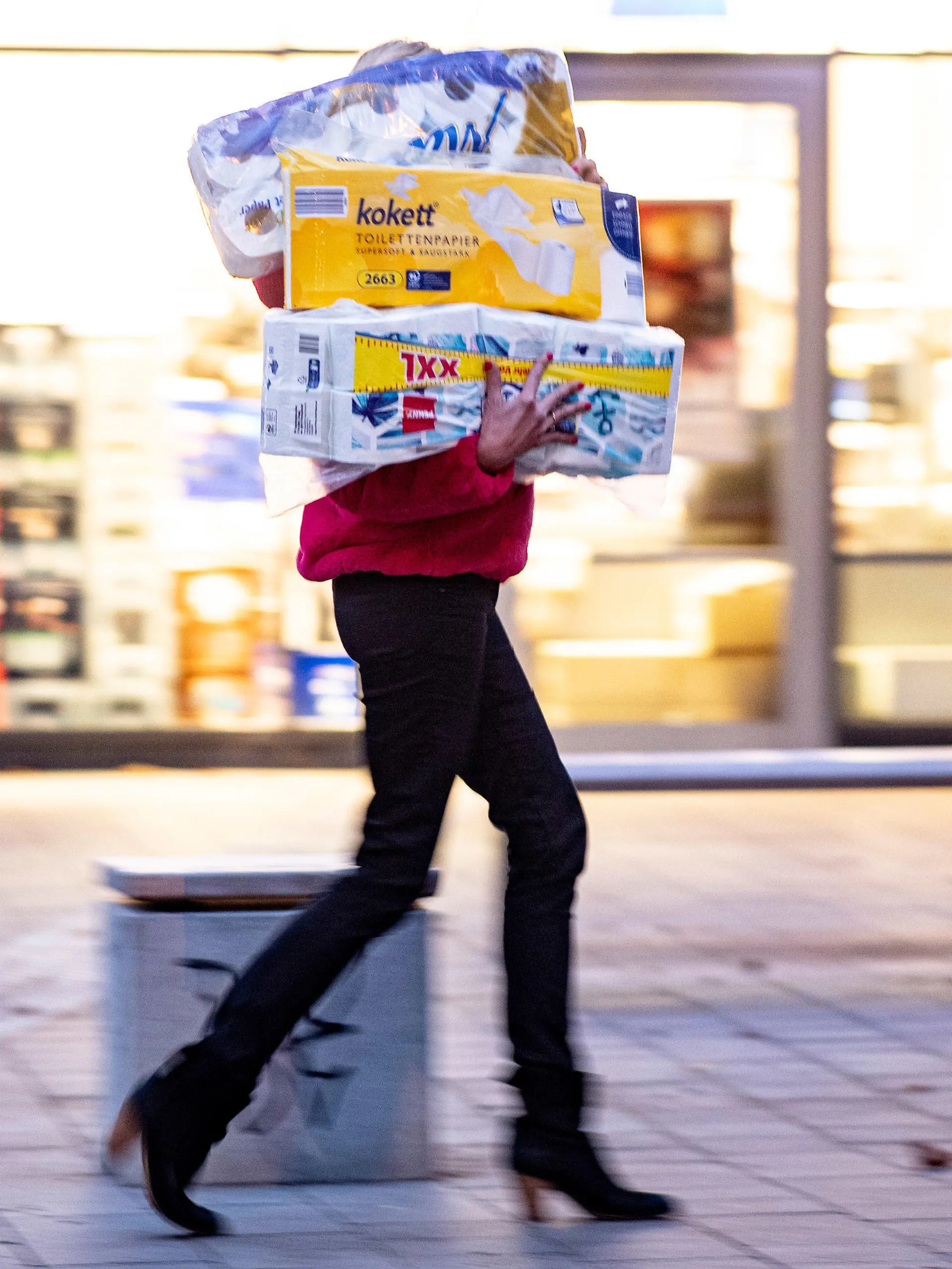 05.11.2020, Hamburg: Ein Frau läuft mit dem Arm voller Klopapierrollen aus einem Drogeriemarkt heraus. Gähnend leere Regale, wo sonst das Toilettenpapier thronte, waren im März dieses Jahres keine Seltenheit in deutschen Supermärkten. Weil viele der strengeren Corona-Regeln ein Comeback feiern, werden mancherorts die weißen Rollen wieder rar. Foto: Axel Heimken/dpa +++ dpa-Bildfunk +++