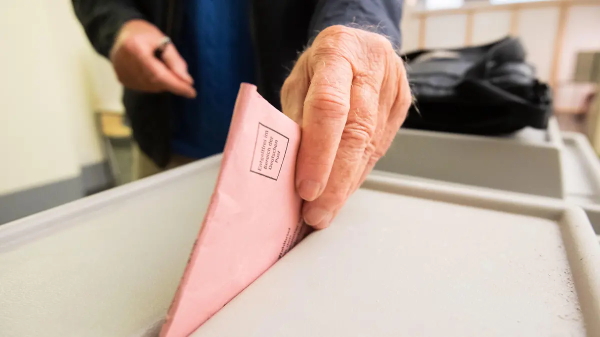 PRODUKTION - 23.08.2021, Niedersachsen, Hannover: Ein Mann wirft seinen Stimmzettel für die Bundestagswahl in eine Urne im Neuen Rathaus. In vielen niedersächsischen Kommunen öffnen haben seit kurzem die Briefwahlstellen geöffnet, in denen Wahlberechtigte ihre Briefwahlunterlagen für die Bundestagswahl und Kommunalwahlen abholen können. Die Stimmzettel können auch vor Ort direkt angekreuzt und die Urnen eingeworfen werden. Foto: Julian Stratenschulte/dpa +++ dpa-Bildfunk +++