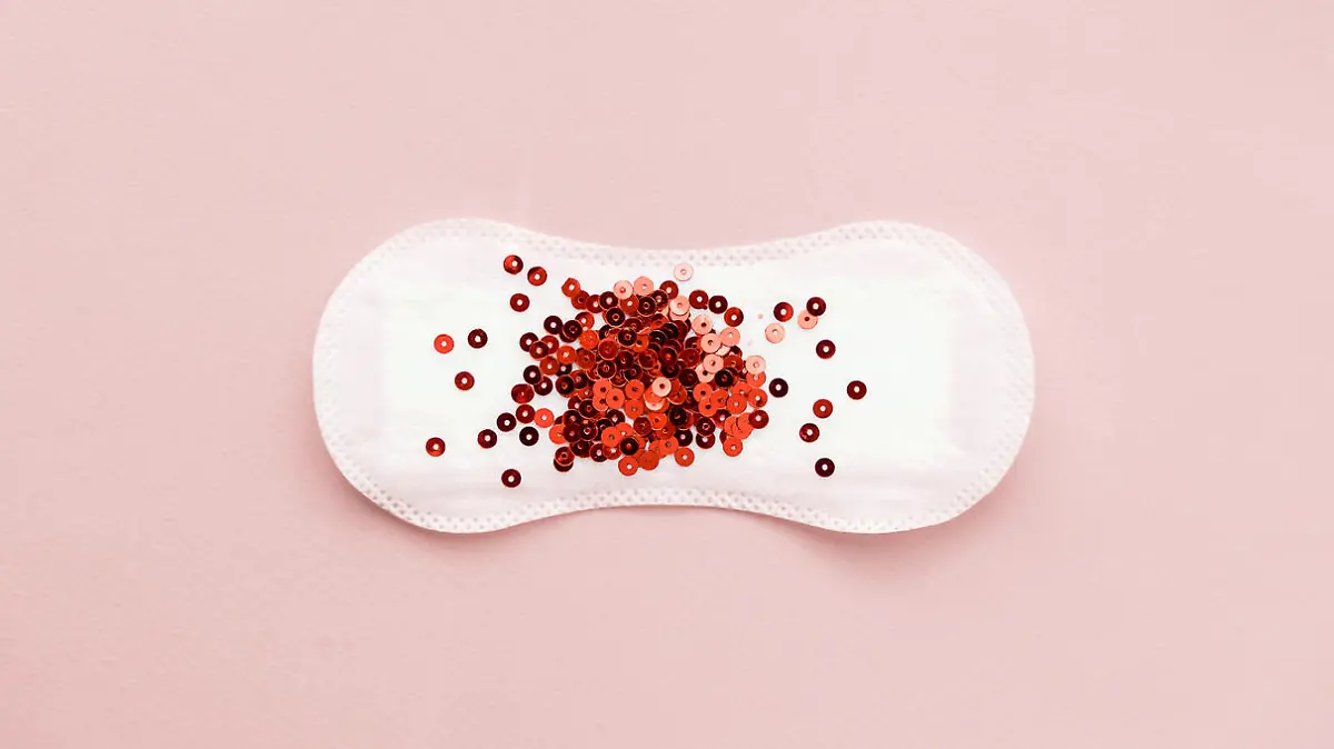 Menstrual pad with red glitter on pastel colored background. Minimalist still life photography concept