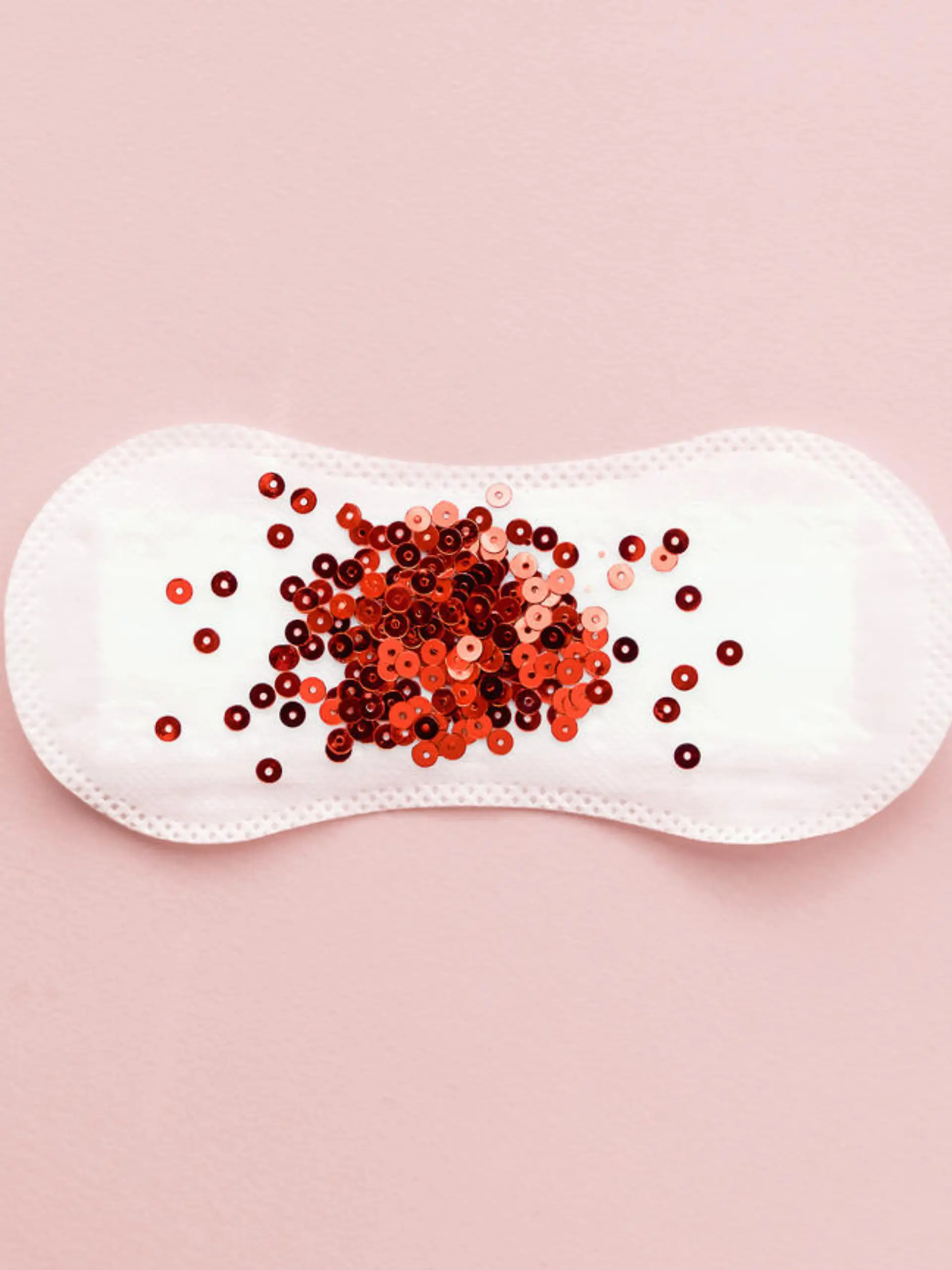 Menstrual pad with red glitter on pastel colored background. Minimalist still life photography concept