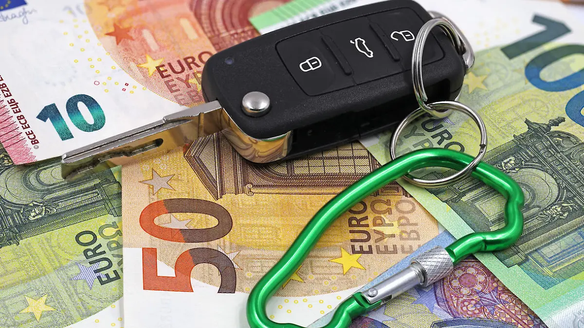 car key with carabiner in car shape on euro money background, concept of car insurance.