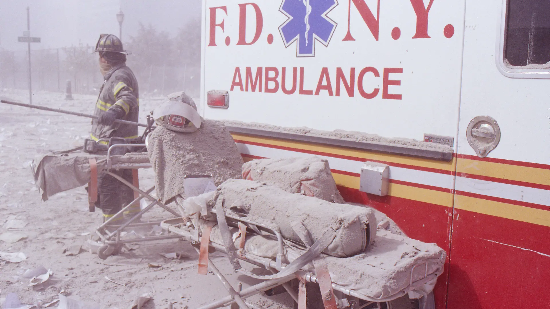 ARCHIV - 11.09.2001, USA, New York: Eine staubbedeckte Krankentrage und ein Feuerwehrmann stehen nach dem Terroranschlag auf das World Trade Center neben einem Rettungswagen. (zu dpa «20 Jahre 9/11: Terroranschläge in den USA») Foto: Randy Taylor/ZUMA Press Wire Service/dpa +++ dpa-Bildfunk +++