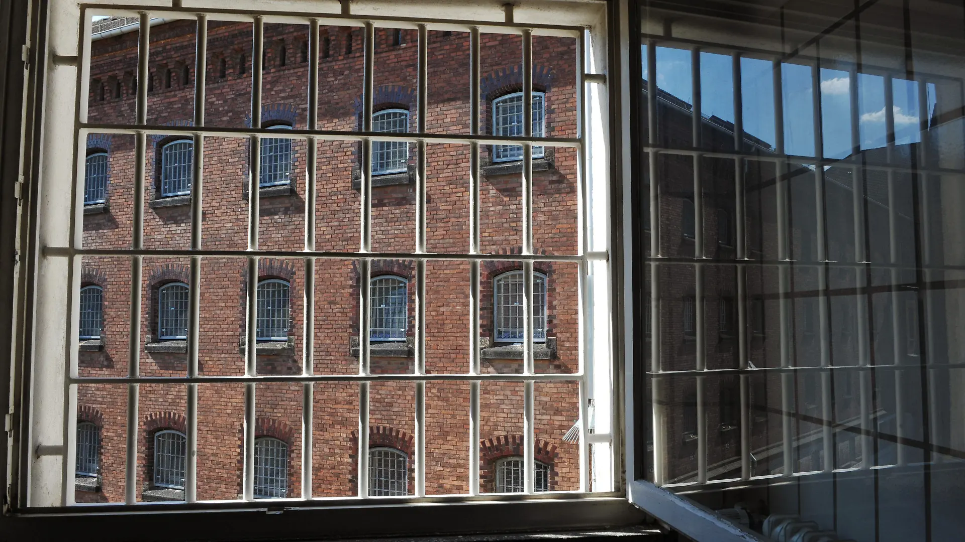 Offen steht am Mittwoch (07.07.2010) ein vergittertes Fenster der JVA-Klinik in Kassel und gibt den Blick frei auf einen Gefängnisflügel der JVA Kassel I. Rechts spiegelt sich der Sommerhimmel. Schweißtreibend ist das Sommerwetter auch für die Gefängnisinsassen. Die Temperaturen steigen bis zum Wochenende wieder auf Werte um die 35 Grad und darüber. Foto: Uwe Zucchi dpa/lhe  +++(c) dpa - Bildfunk+++